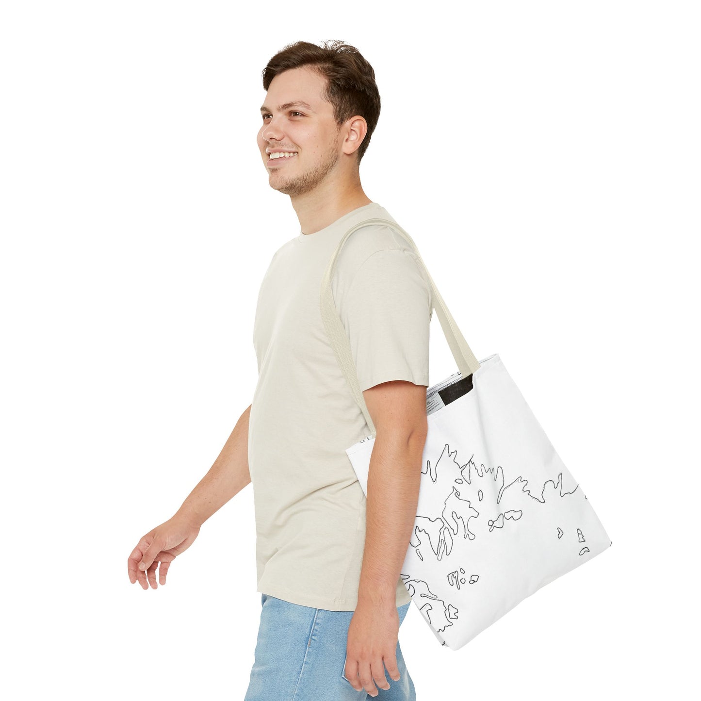 This is the Beige 13" x 13" Flowers Tote Bag by Storm Garden Studio. The tote has color matched straps, abstract line work which is outlines of flowers, all over print. The colors are white and black. A brunette man is walking towards the left wearing the white tee and light jeans. He is looking towards the left and smiling with the tote over his shoulder. He is against a white background.
