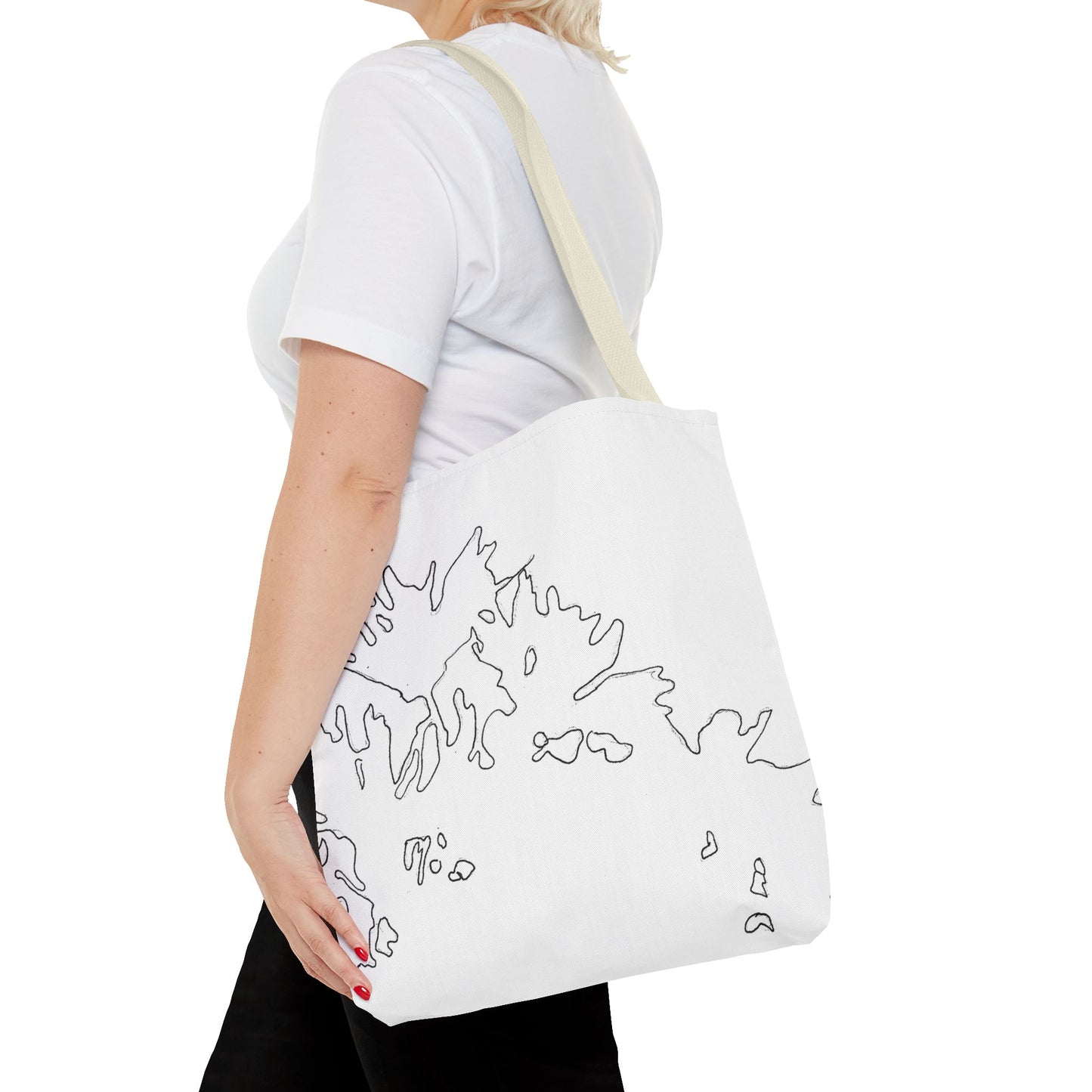 This is the Beige 16" x 16" Flowers Tote Bag by Storm Garden Studio. The tote has color matched straps, abstract line work which is outlines of flowers, all over print. The colors are white and black. A blond haired lady is walking towards the left wearing a white tee, black pants, hand on the tote and image is from the shoulders down. She is against a white background.