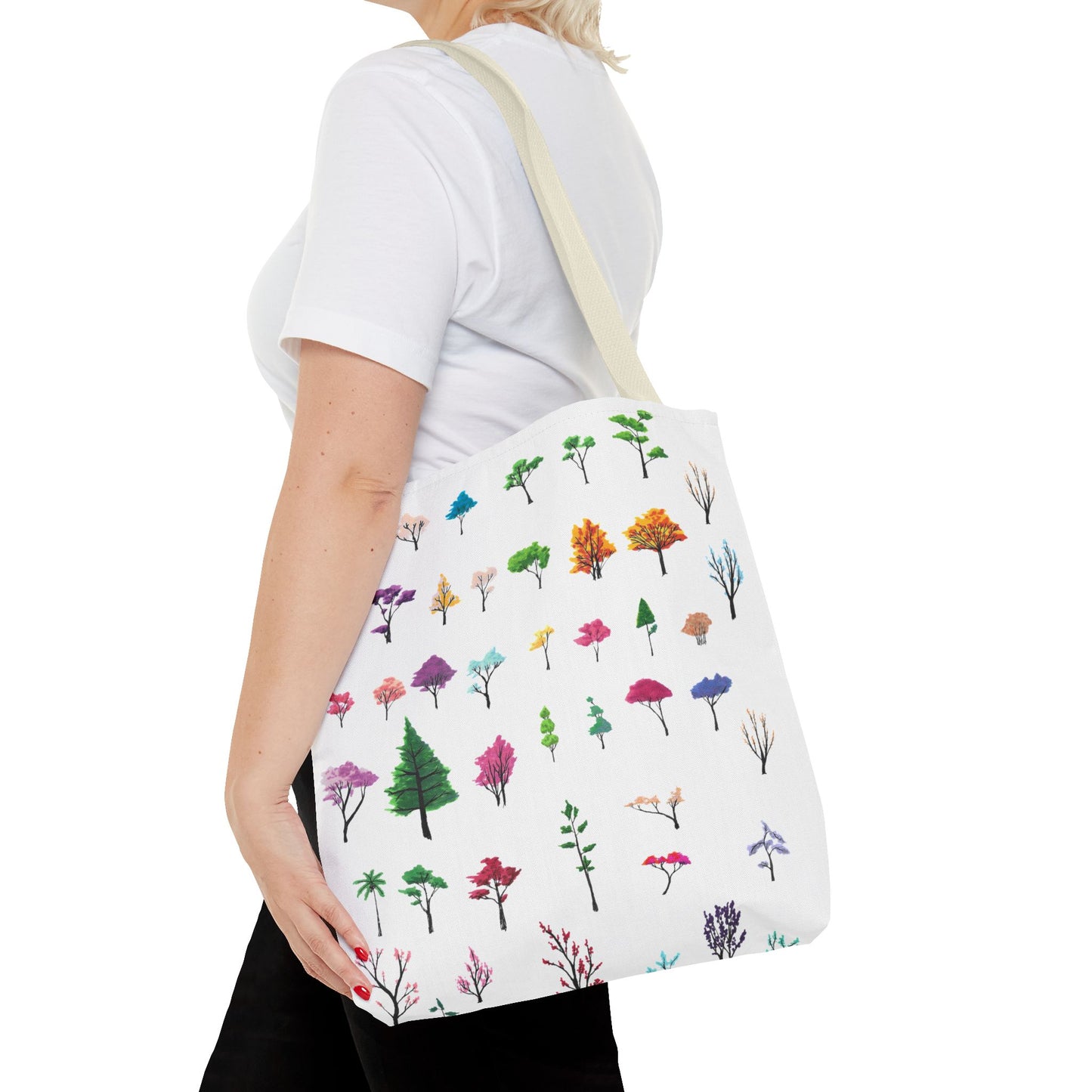 This is the Beige 16" x 16" Study of Trees Tote with color matched handles by Lee Hansheng Studios. There are a variety of tree illustrations from blooming fruit trees to deciduous and evergreens. The trees are colored pinks, purples, greens, yellows, blues and oranges on a white background. The tote is over the shoulder of a short blonde haired woman who has a white tee and black pants. Her hand is on the tote and image only shows from the neck to upper thigh.
