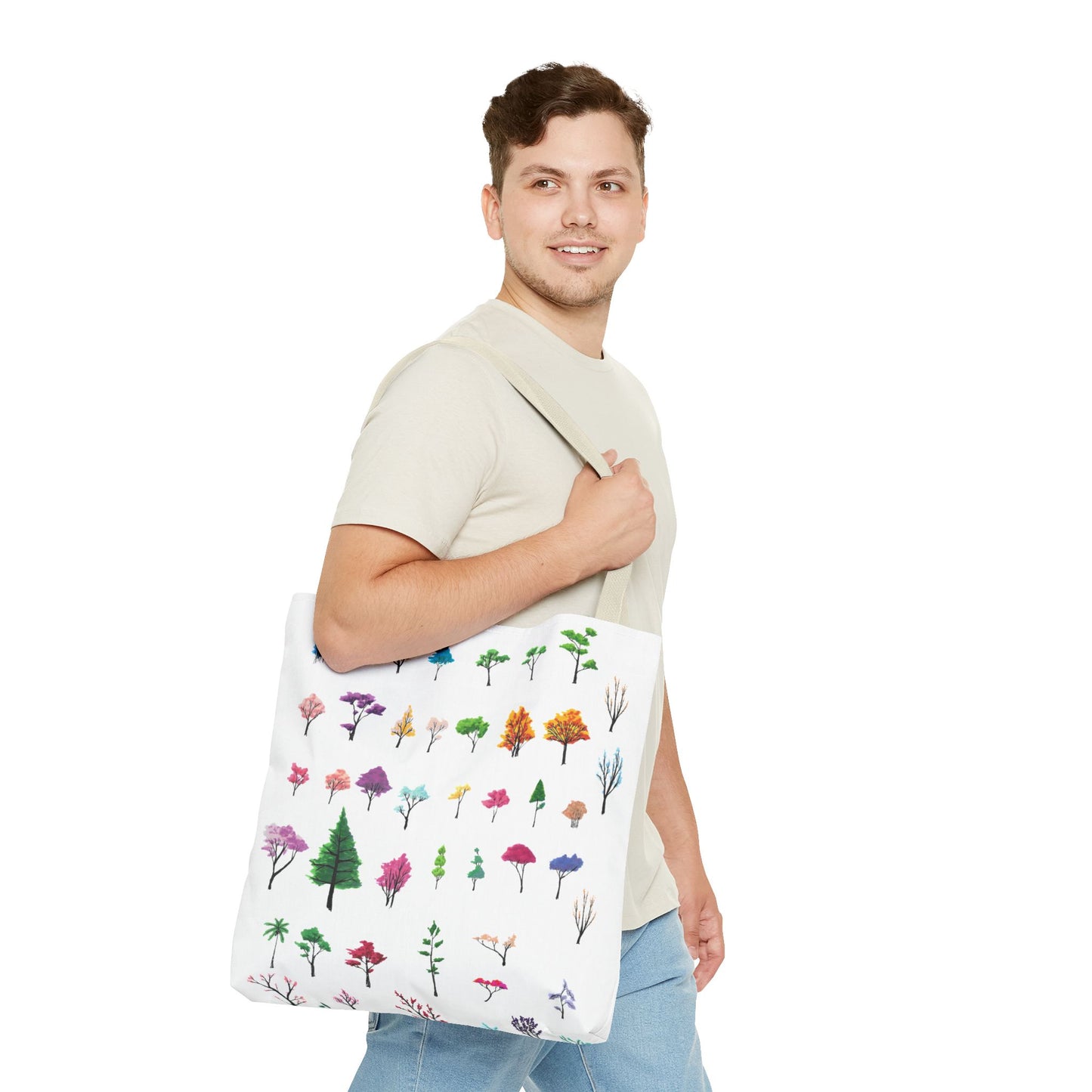 The Beige 16" x 16" Study of Trees Tote Bag has color matched handles. A man with a smile, short wavy brown hair, beige tee plus jeans with tote around their shoulder and walking to the right against a white background. The design is by Lee Hansheng Studios. There are a variety of tree illustrations from blooming fruit trees to deciduous and evergreens. The trees are colored pinks, purples, greens, yellows, blues and oranges on a white background.