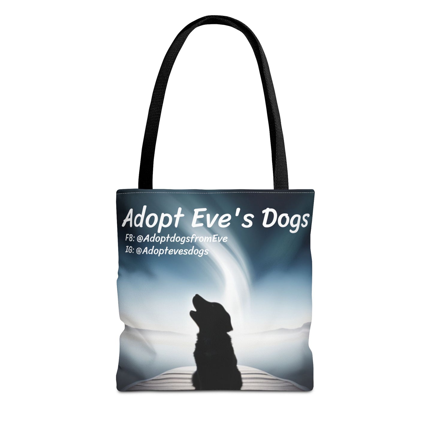 This is the Black 13" x 13" Adopt Eve's Dogs Tote with color matched handles. This is an all around print tote with "Adopt Eve's Dogs" and socials on the top in white. The print is of a shadow of a golden retriever looking to the left on a pier towards water with mountains surrounding it. The tote is against a white background.
