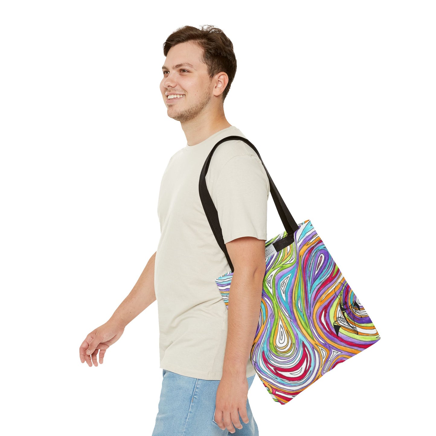 This is the Black 16" x 16" Oil Spill Tote bag by Storm Garden Studios. A smiling brunette man in white shirt, and blue jeans, side view walking to the left carrying the bag with color matched straps, abstract colors and line work, all over print. The colors are lime green, orange, light blue, dark red, purple, white and black. Storm Garden Studio logo printed in black on bottom right of tote bag. He is against a white background.