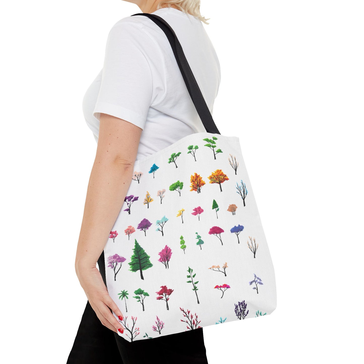 This is the Black 16" x 16" Study of Trees Tote with color matched handles by Lee Hansheng Studios. There are a variety of tree illustrations from blooming fruit trees to deciduous and evergreens. The trees are colored pinks, purples, greens, yellows, blues and oranges on a white background. The tote is over the shoulder of a short blonde haired woman who has a white tee and black pants. Her hand is on the bag and image only shows from the neck to upper thigh.