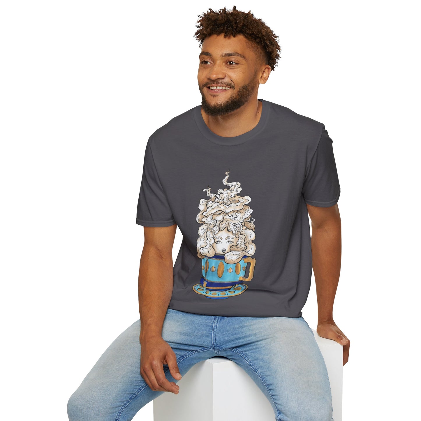 This is the Charcoal Earl Grey Softstyle T-Shirt by Chris Foster Design. It comes in sizes XS-5XL. The illustration is of a gold, light blue and dark blue teacup with a tan, yellow and white steam. The steam is swirly and goes up and outwards. In the middle is a lady's face. A smiling man sitting on a white podium with one hand on the back edge, light jeans, looking to the left and wearing the t-shirt.