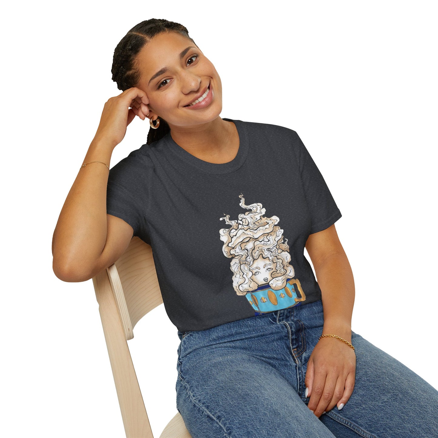 This is the Dark Heather Grey Earl Grey Softstyle T-Shirt by Chris Foster Design. It comes in sizes XS-5XL. The illustration is of a gold, light blue and dark blue teacup with a tan, yellow and white steam. The steam is swirly and goes up and outwards. In the middle is a lady's face. A smiling lady is sitting on a light wood chair with the backrest to the left, elbow on the back rest, dark jeans, looking to the front and wearing the t-shirt.