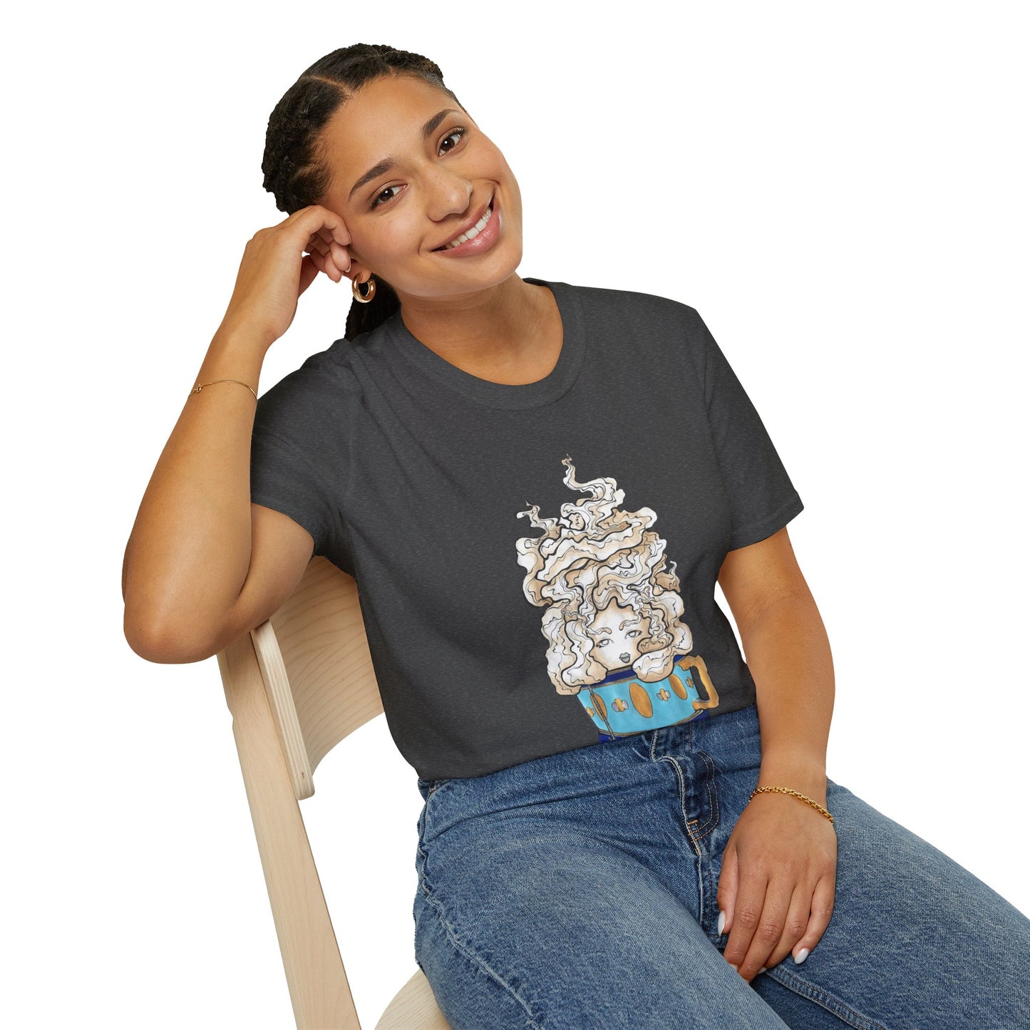 This is the Dark Heather Earl Grey Softstyle T-Shirt by Chris Foster Design. It comes in sizes XS-5XL. The illustration is of a gold, light blue and dark blue teacup with a tan, yellow and white steam. The steam is swirly and goes up and outwards. In the middle is a lady's face. A smiling lady is sitting on a light wood chair with the backrest to the left, elbow on the back rest, dark jeans, looking to the front and wearing the t-shirt.