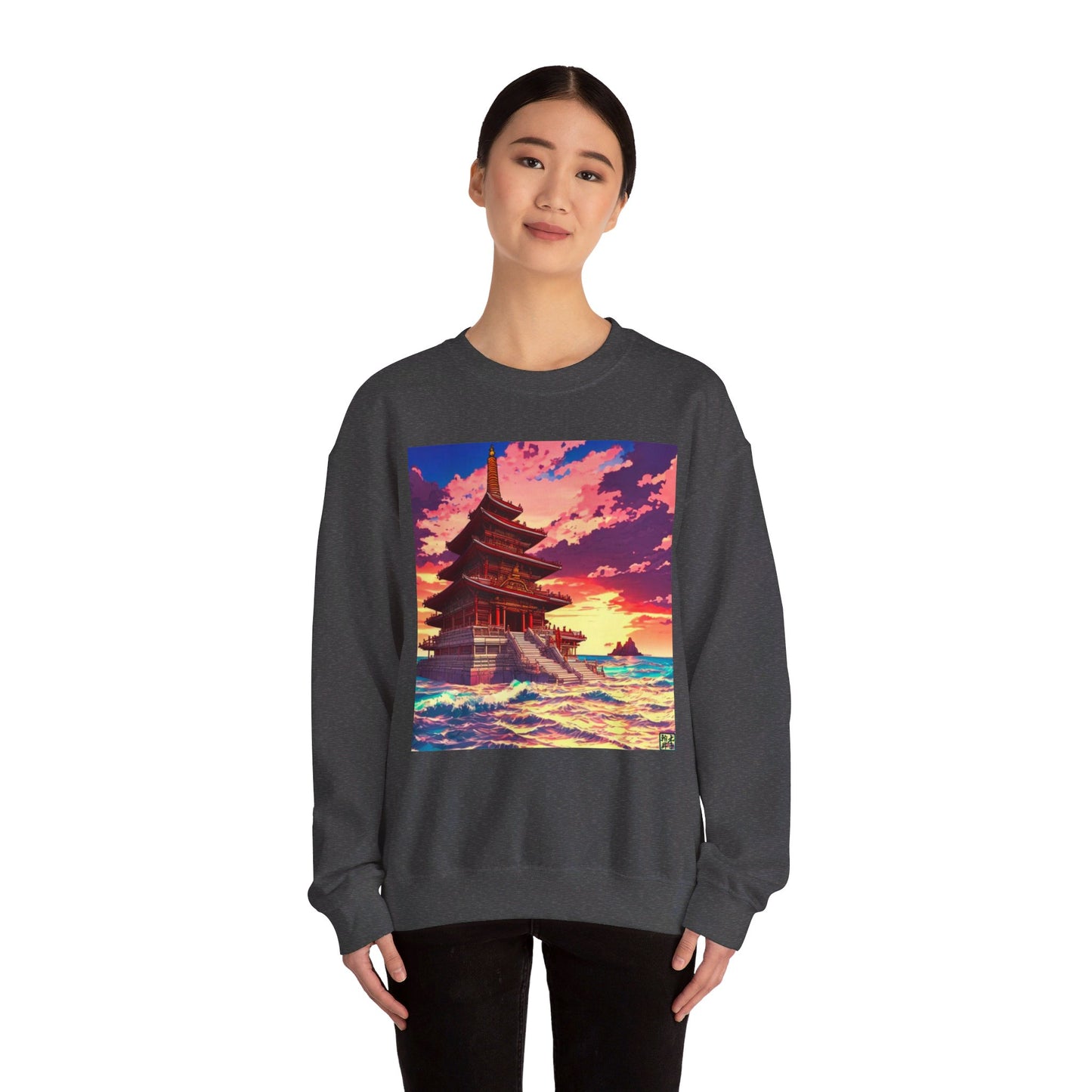 This is the Dark Heather Temple on the Sea Heavy Blend Crewneck Sweatshirt by Lee Hansheng Studios. This is an image of the front of the sweatshirt. A lady with black hair tied, a smile, black pants and hands on her sides. The illustration has a temple with 4 stories on the left surround by crashing waves of the sea, mountains on the right in the background. The Lee Hansheng logo is on the bottom right on the illustration outlined in blue. The colors are a mix of blues, pinks, reds and yellows.