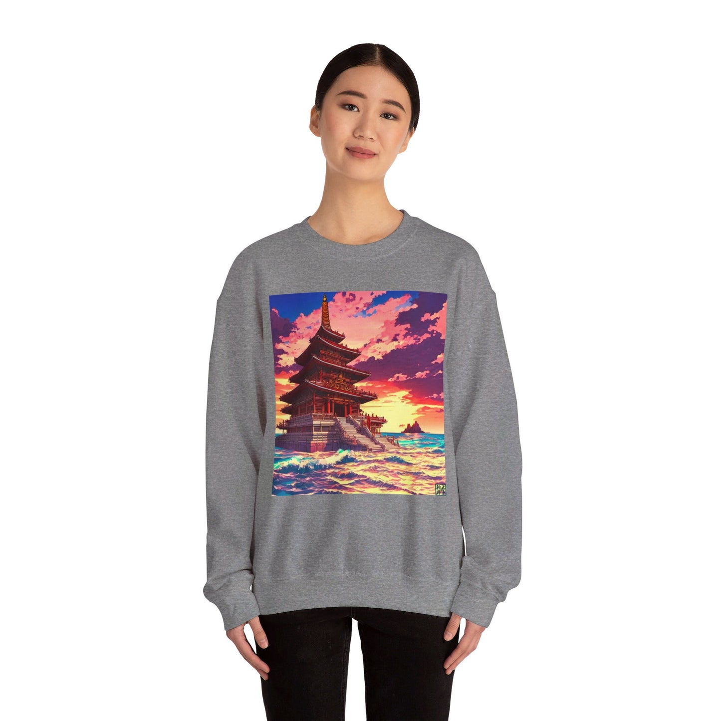 This is the Graphite Heather Temple on the Sea Heavy Blend Crewneck Sweatshirt by Lee Hansheng Studios. This is an image of the front of the sweatshirt. A lady with black hair tied, a smile, black pants and hands on her sides. The illustration has a temple with 4 stories on the left surround by crashing waves of the sea, mountains on the right in the background. The Lee Hansheng logo is on the bottom right on the illustration outlined in blue. The colors are a mix of blues, pinks, reds and yellows.