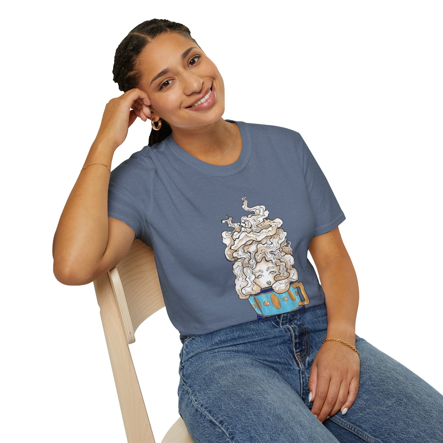 This is the Heather Indigo Earl Grey Softstyle T-Shirt by Chris Foster Design. It comes in sizes XS-5XL. The illustration is of a gold, light blue and dark blue teacup with a tan, yellow and white steam. The steam is swirly and goes up and outwards. In the middle is a lady's face. A smiling lady is sitting on a light wood chair with the backrest to the left, elbow on the back rest, dark jeans, looking to the front and wearing the t-shirt.