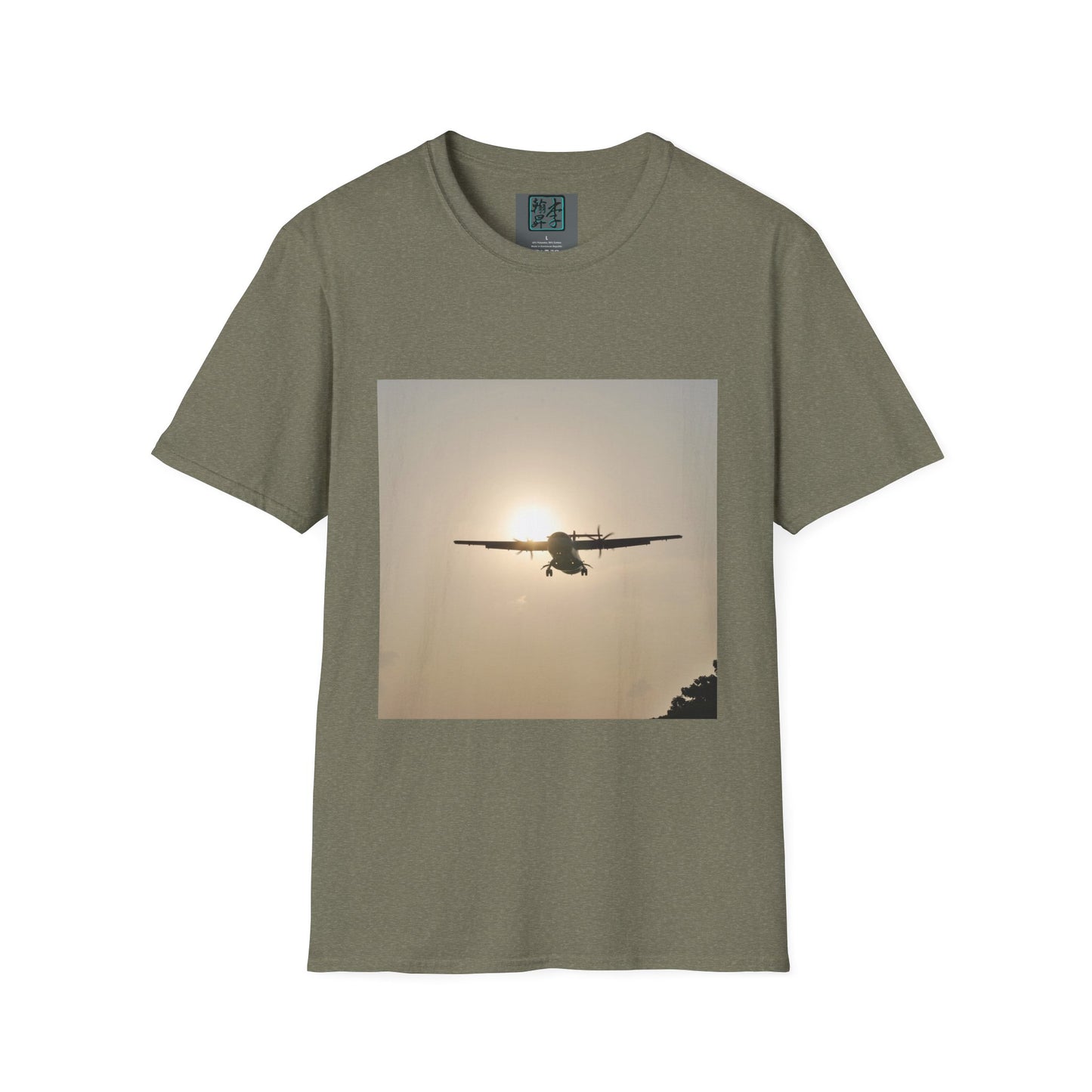 This is the Heather Military Green Landing T-Shirt by Lee Hansheng Studios. This is an image of the front folded. On the inside of the shirt is the logo for the studio printed in black outlined in blue, gray size label with the print being white. The illustration is a rectangular design of an airplane landing. There is an orange/yellow sun with the shadowed plane. Some trees on the right end corner. The shirt is against a white background.