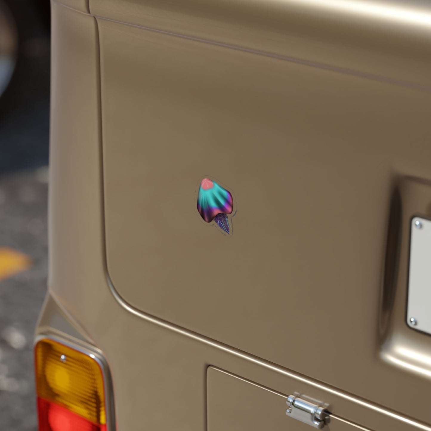 A 2" x 2" die cut transparent sticker of a pink, blue and purple jellyfish on the bumper of a car.