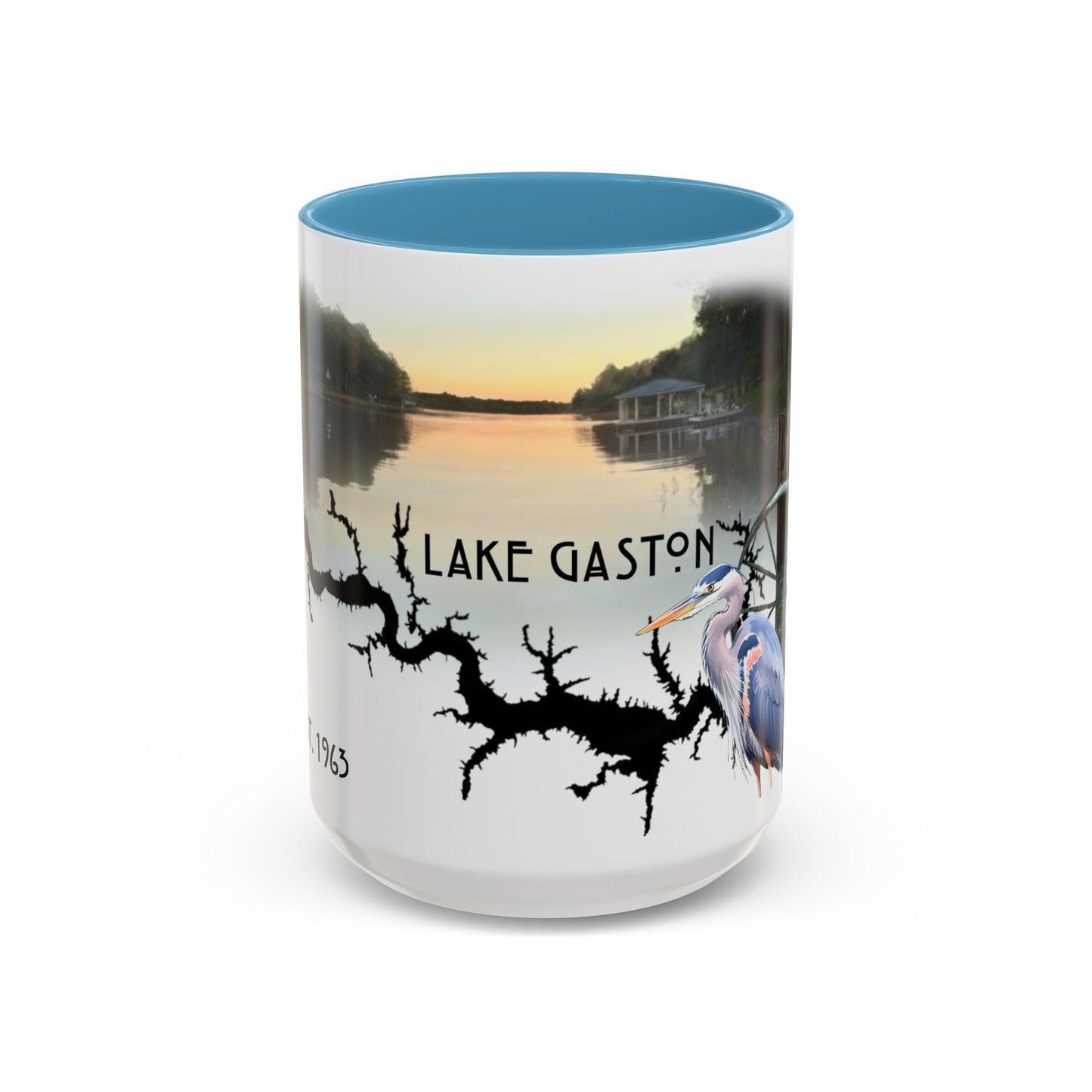 This is the 15oz Light Blue Lake Gaston Mug. It is an illustration by Lee Hansheng Studios. The picture is showing the front side of the mug. The inside of mug are color matched too. The mug is all white except for the illustration and handle. The illustration shows the lake on a horizon, the words "Lake Gaston", a black branch, and a blue heron on the right. The colors are orange, blue and green for the landscape. The mug is against a white background in the picture.