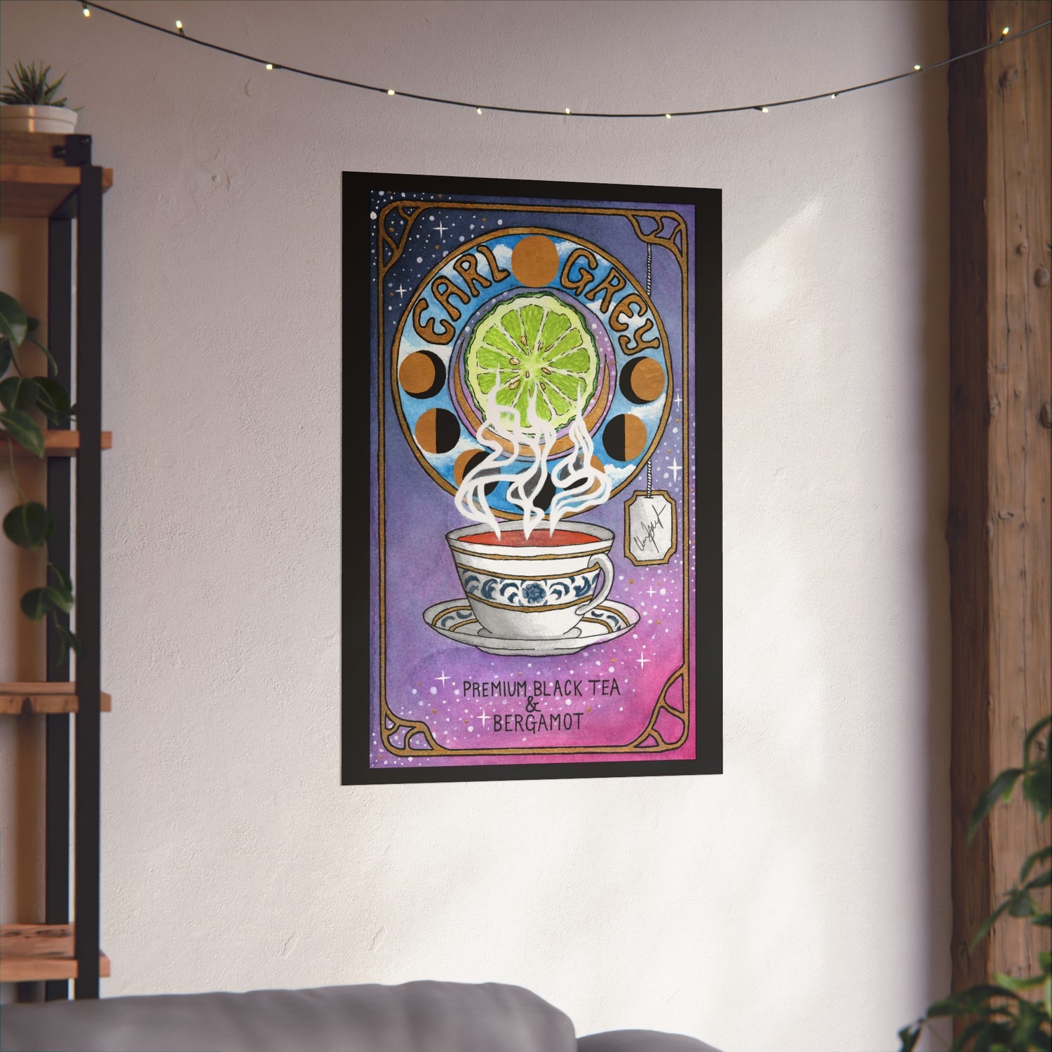 This is the Matte 24" x 36" Earl Grey Poster by Chris Foster Design.The illustration has a steaming cup of brown tea,saucer,blue/gold flower leaves design,"Premium black tea & bergamot"below cup,phases of the moon in gold/black,"Earl Grey" between the full moon,lime slice in the middle,a tea bag,studio's signature printed in black on a yellow/white tag,white stars twinkling in the background and gold/black border.Poster is angled on white wall,fairy lights, wood frame and industrial shelf on either side.