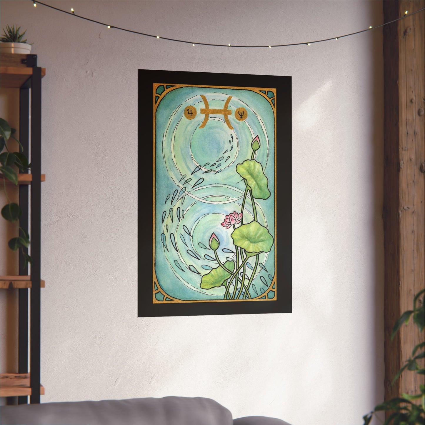 This is the Matte 24" x 36" Pisces Poster by Chris Foster Design. The illustration is designed like a tarot card, has a black border, gold frame, a pond, two circular ripples of water, 1 bloomed flower, 2 buds and 3 leaves combined trailing up on the right with seeds running down the pond, Pisces symbols on the top in gold. Poster is angled on white wall,fairy lights above, wood frame to the right,wood/industrial shelf with ivy plants and succulent with white pot on left side and gray sofa below shelf.