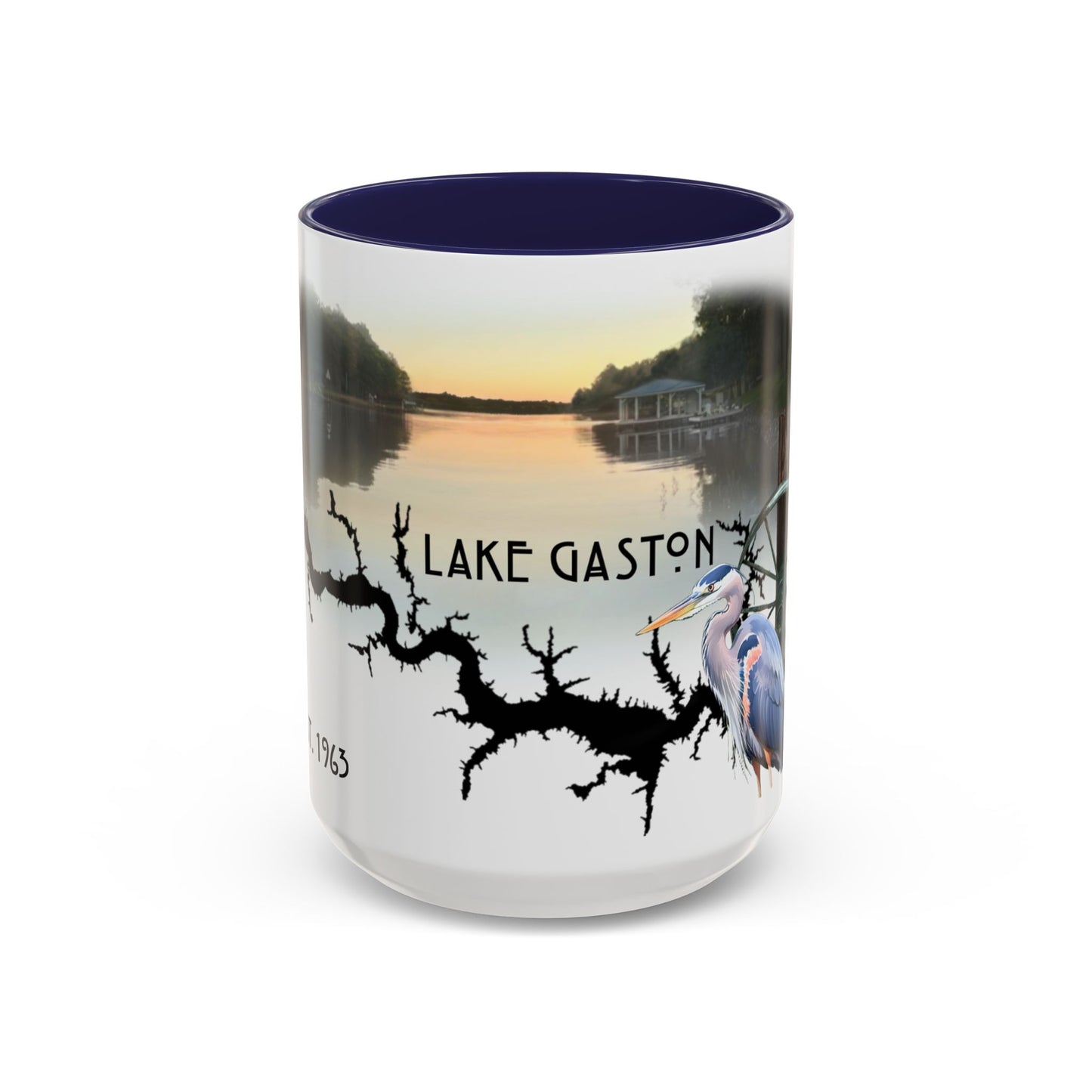 This is the 15oz Navy Lake Gaston Mug. It is an illustration by Lee Hansheng Studios. The picture is showing the front side of the mug. The inside of mug are color matched too. The mug is all white except for the illustration and handle. The illustration shows the lake on a horizon, the words "Lake Gaston", a black branch, and a blue heron on the right. The colors are orange, blue and green for the landscape. The mug is against a white background in the picture.