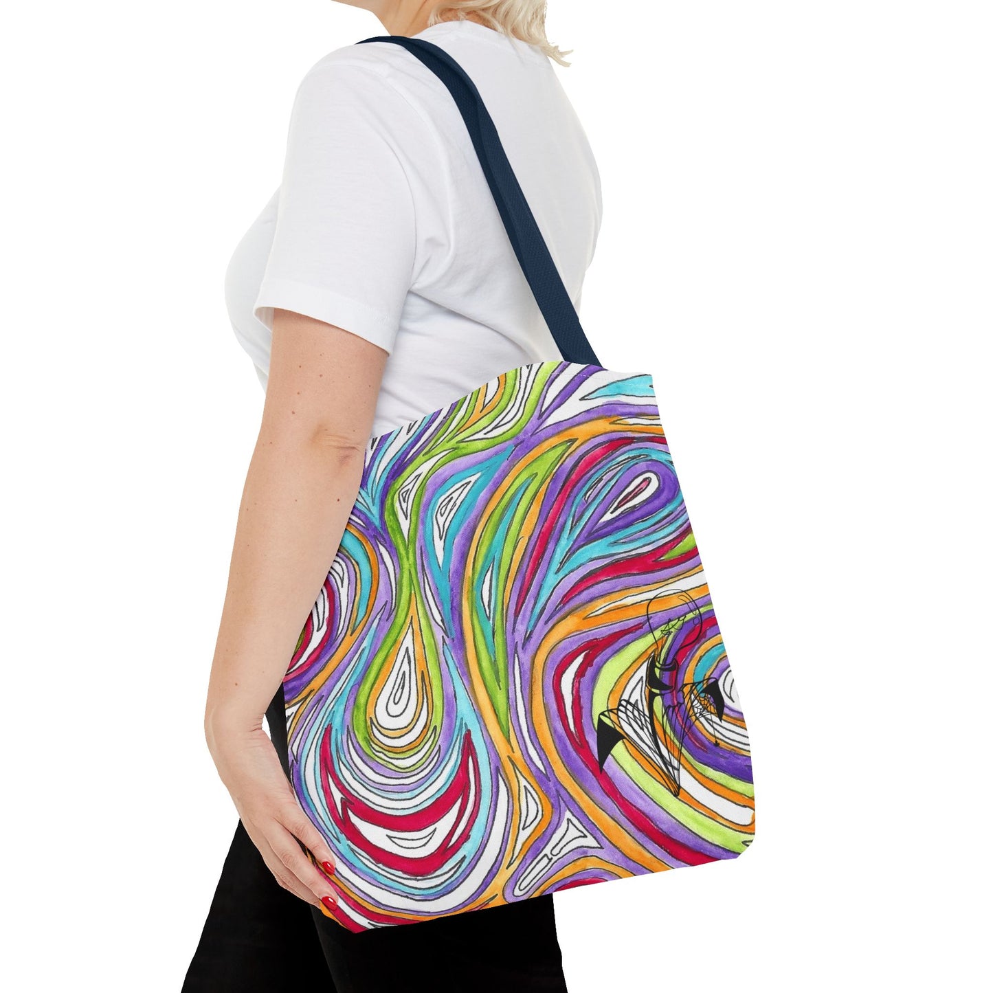 This is the Navy 18" x 18" Oil Spill Tote bag by Storm Garden Studios. A woman walking towards the left, short blonde hair, in white shirt, and black pants, one hand on the tote and carrying the bag with color matched straps, abstract colors and line work, all over print. The colors are lime green, orange, light blue, dark red, purple, white and black. Storm Garden Studio logo on bottom right of tote bag printed in black. She is against a white background.