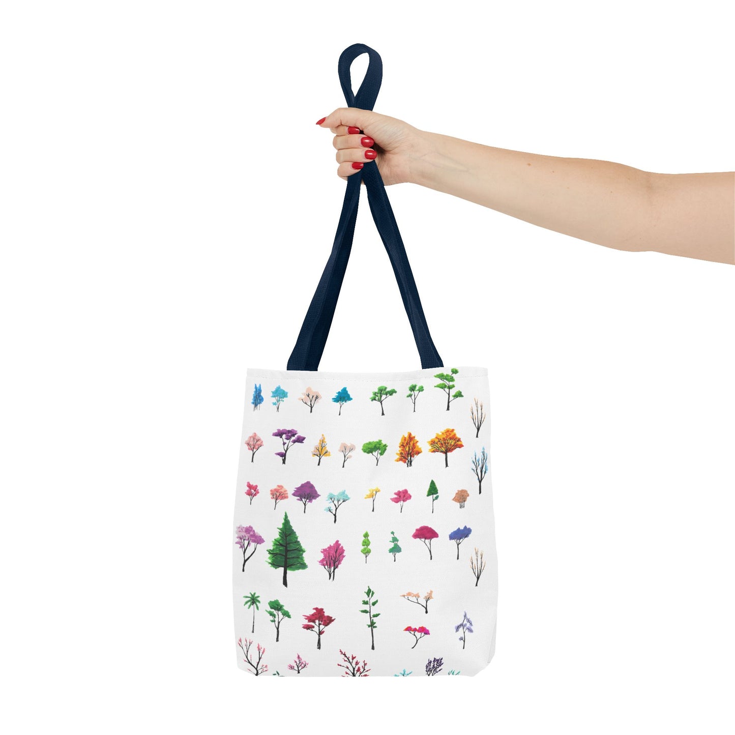 The Navy 16" x 16" Study of Trees Tote with color matched handles by Lee Hansheng Studios. There are a variety of tree illustrations from blooming fruit trees to deciduous and evergreens. The trees are colored pinks, purples, greens, yellows, blues and oranges on a white background tote. A woman's hand with red nail polish is grabbing the handles. Her arm is outstretched to the middle. The tote is against a white background.