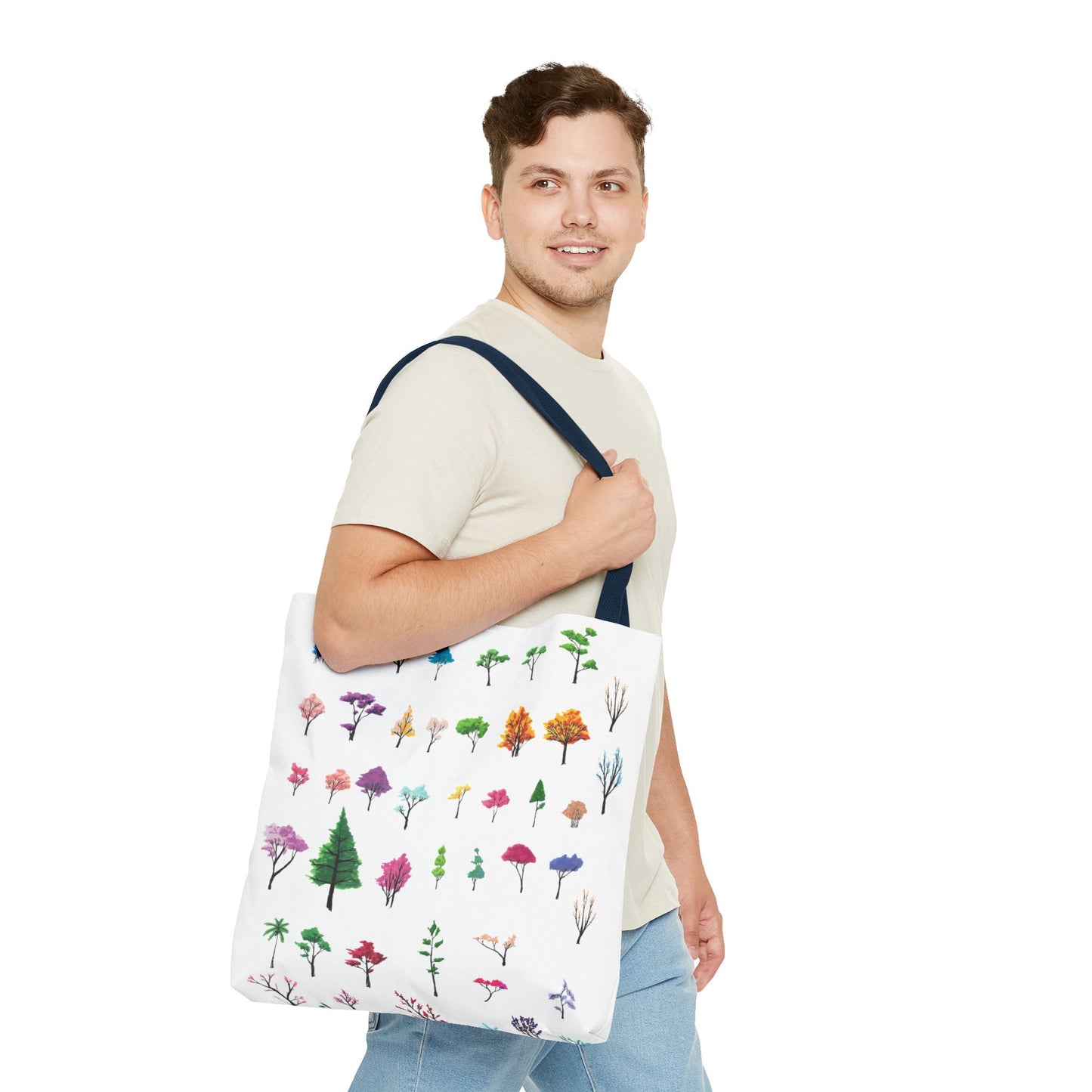 The Navy 16" x 16" Study of Trees Tote Bag has color matched handles. A man with a smile, short wavy brown hair, beige tee plus jeans with tote around their shoulder and walking to the right against a white background. The design is by Lee Hansheng Studios. There are a variety of tree illustrations from blooming fruit trees to deciduous and evergreens. The trees are colored pinks, purples, greens, yellows, blues and oranges on a white background.