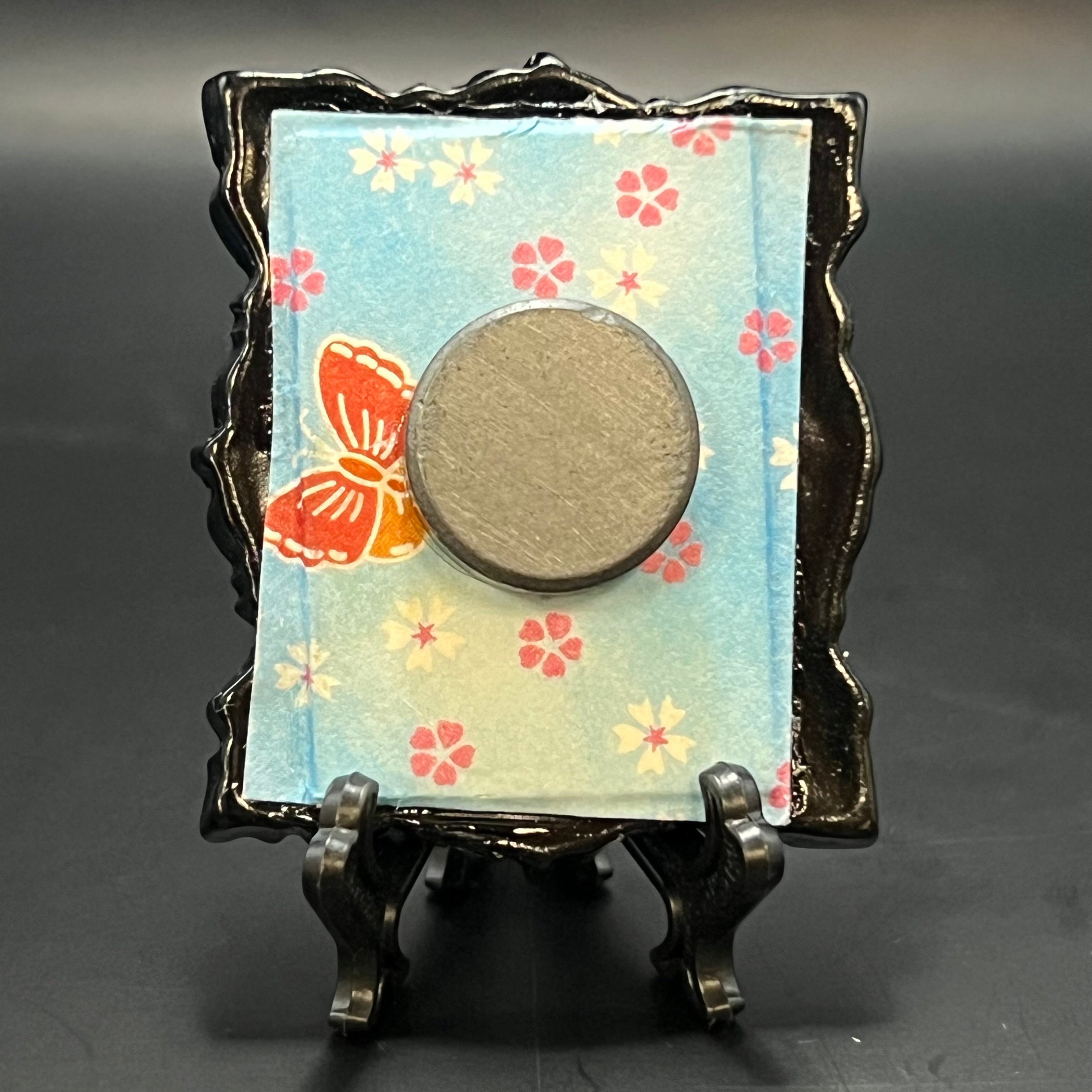 Close-up of the textured brushwork and vibrant plum blossom details on the mini painting's framed corner, showcasing