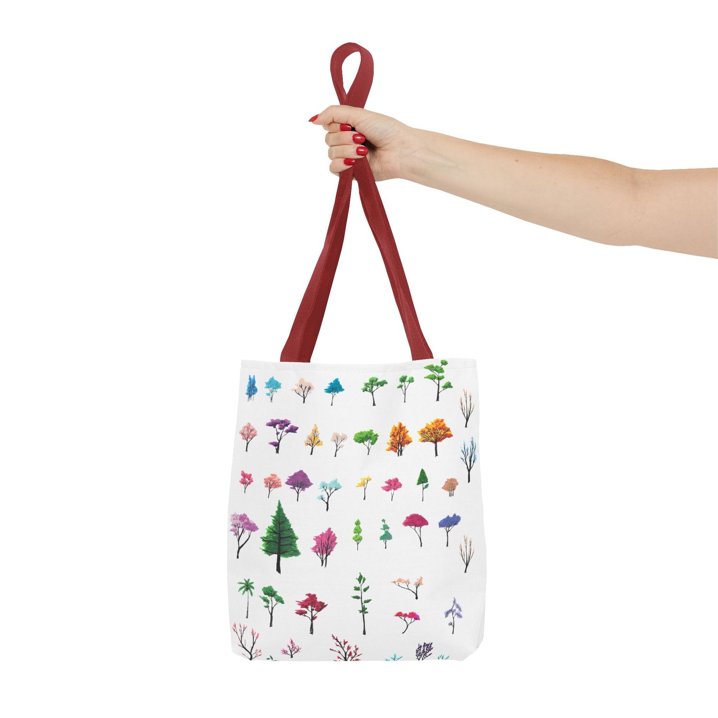 The Red 16" x 16" Study of Trees Tote with color matched handles by Lee Hansheng Studios. There are a variety of tree illustrations from blooming fruit trees to deciduous and evergreens. The trees are colored pinks, purples, greens, yellows, blues and oranges on a white background tote. A woman's hand with red nail polish is grabbing the handles. Her arm is outstretched to the middle. The tote is against a white background.