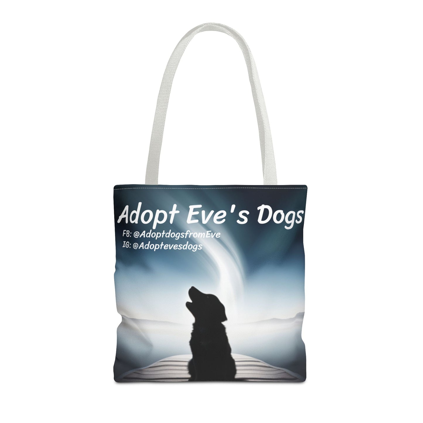 This is the White 16" x 16" Adopt Eve's Dogs Tote with color matched handles. This is an all around print tote with "Adopt Eve's Dogs" and socials on the top in white. The print is of a shadow of a golden retriever looking to the left on a pier towards water with mountains surrounding it. The tote is against a white background.