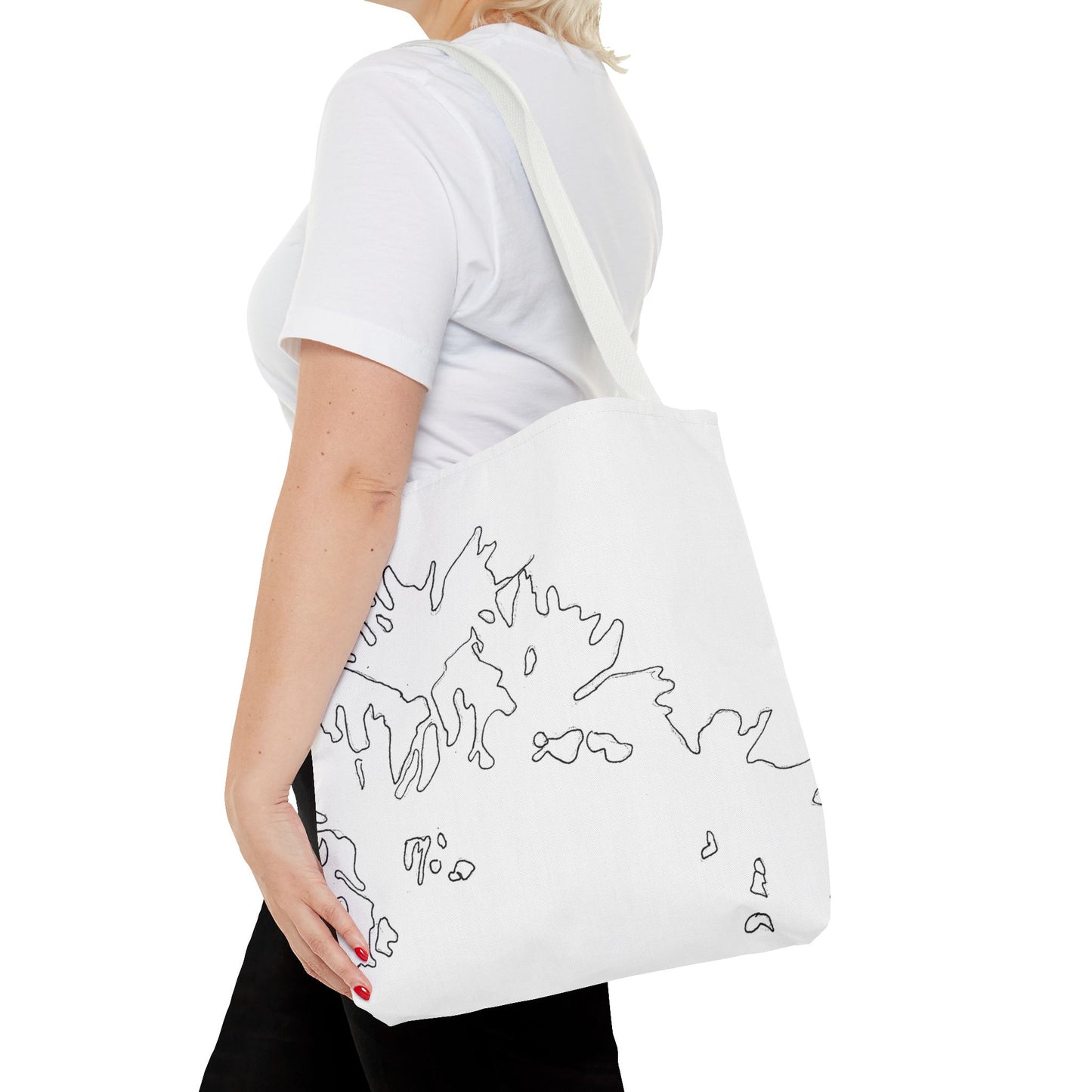 This is the White 16" x 16" Flowers Tote Bag by Storm Garden Studio. The tote has color matched straps, abstract line work which is outlines of flowers, all over print. The colors are white and black. A blond haired lady is walking towards the left wearing a white tee, black pants, hand on tote and image is from the shoulders down. She is against a white background.