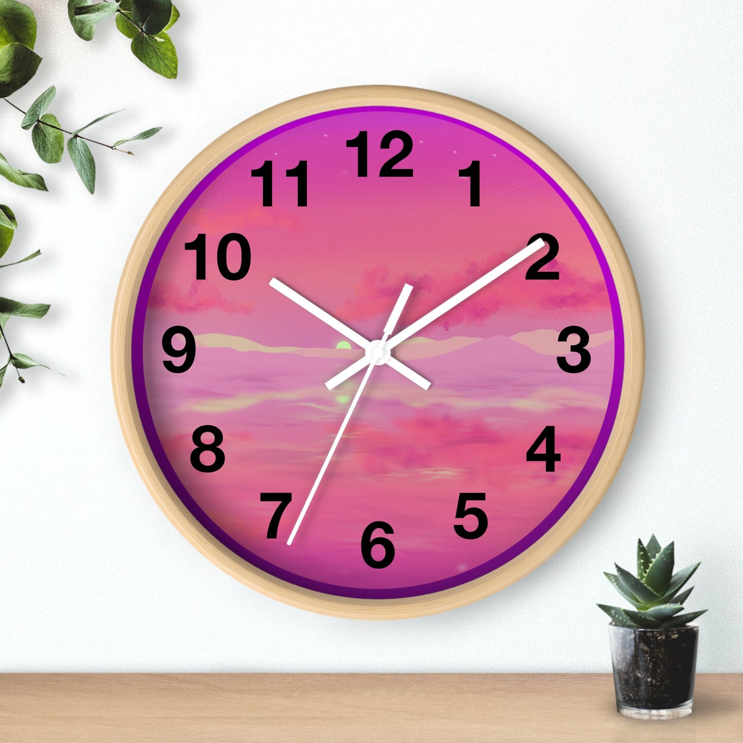 This is the 10" Wooden Base Pink Dreamscape Wall Clock with white hands by Lee Hansheng Studios.The front of the image with two white clock hands, black numerals and the illustration behind it.The illustration has the sky and clouds. Different pinks and hues blended into the clouds and spreads outwards.There are dark purples on the side and yellows near the middle of the art piece. It is on a white background with leaves to the left, succulent plan on the right with a wooden board.