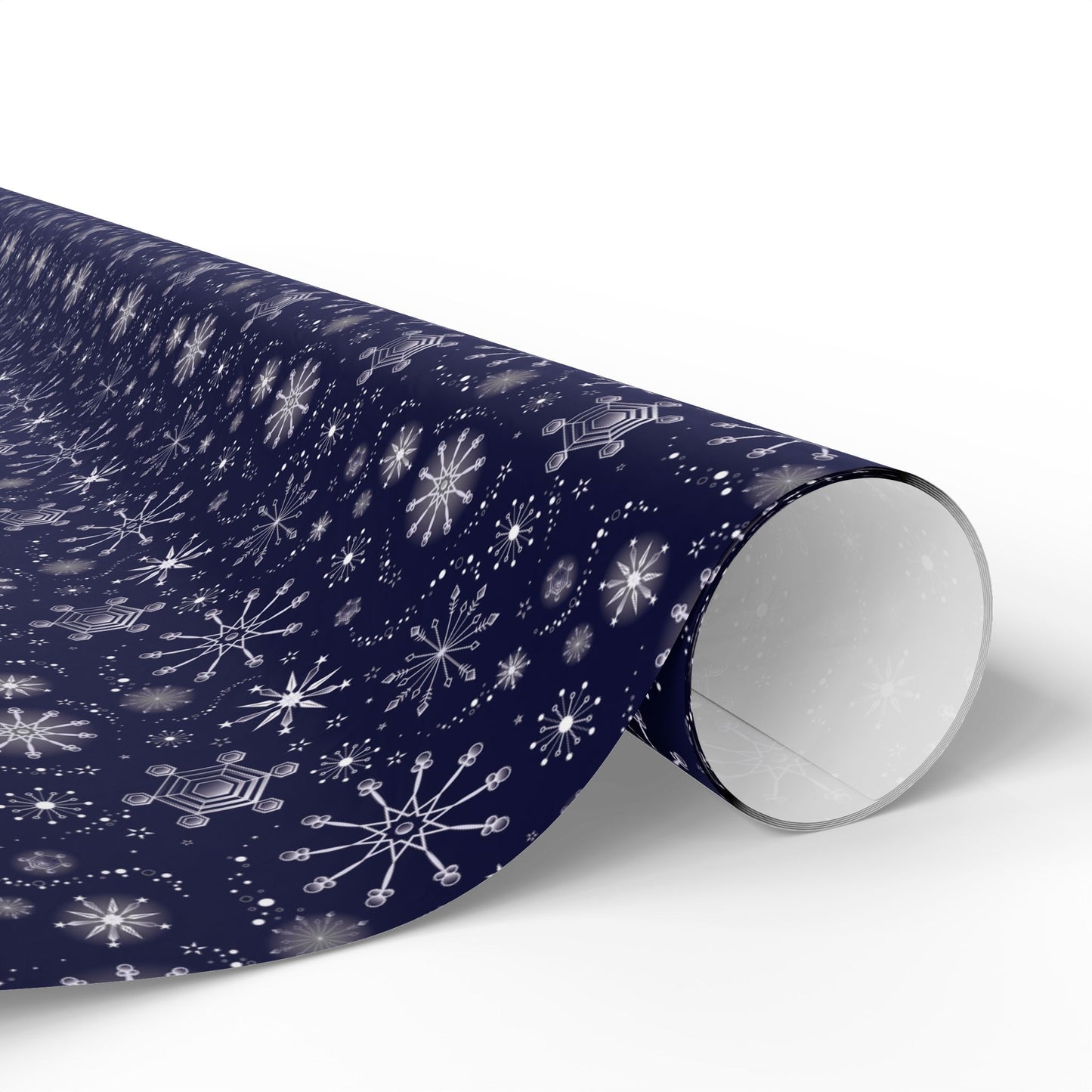 This is the glossy 30" x 36" Winter Blizzard Gift Wrap. The image is a roll of wrapping paper and the design at an angle. The background is white. The design are different types of snowflakes with different sizes of circles within each flake. The wrapping paper is dark blue and the snowflakes and design are all white.