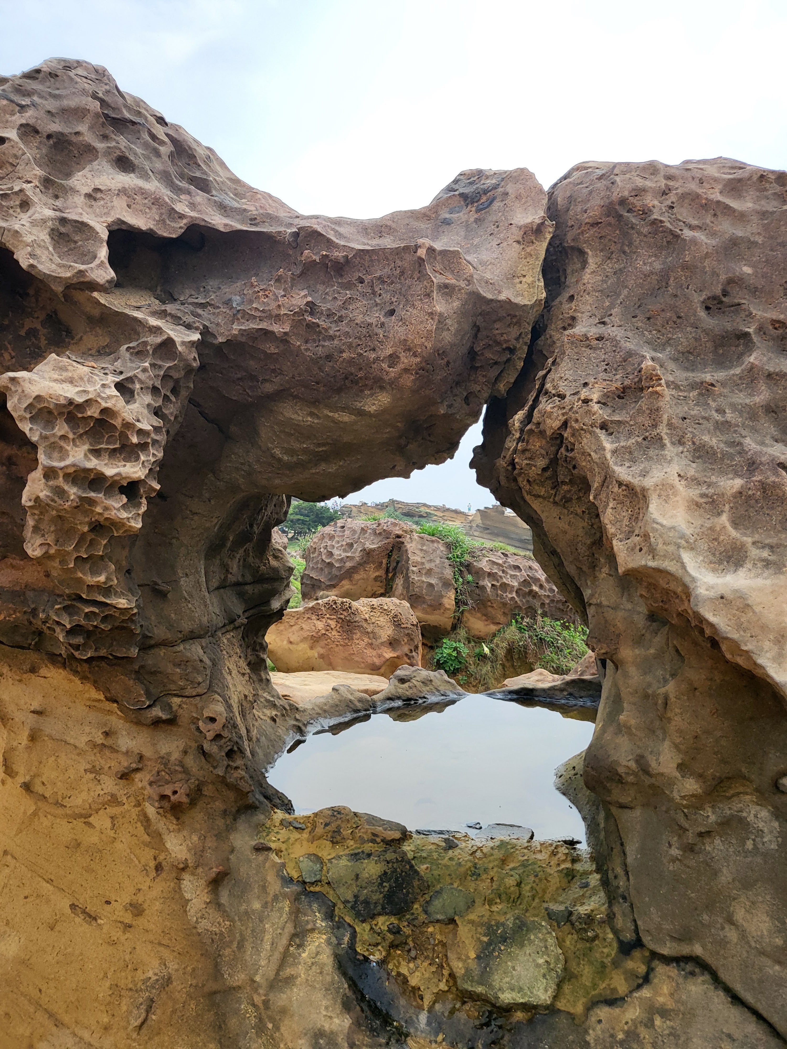 This is an image when Maizi was traveling in Taiwan. We went to see Jiufen, the Miyazaki film was inspired by. This is a beach near there that had cool rock formations. This is an image of a circular one with rocks in the background.
