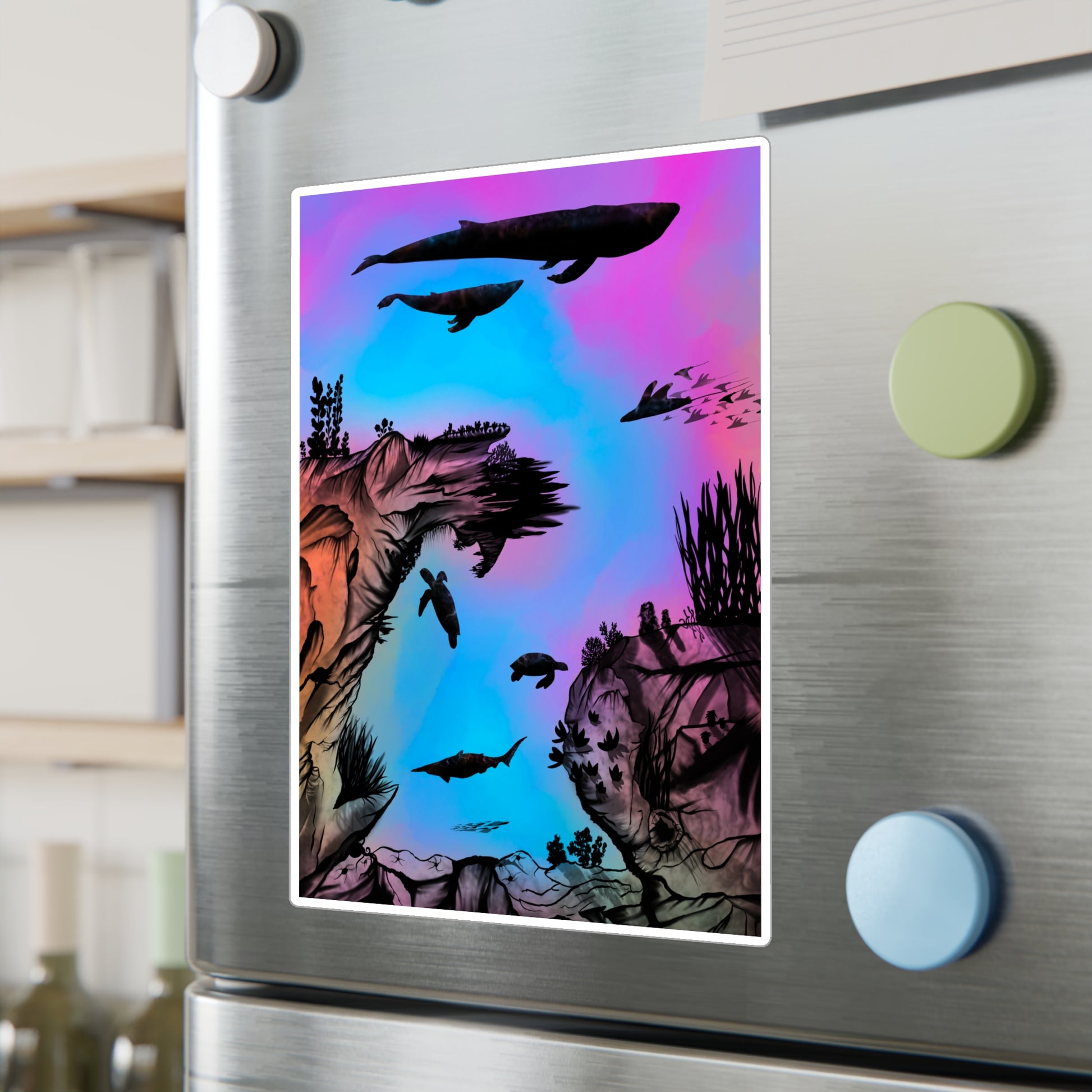 A 8" x 10" kiss-cut vinyl decal underwater seascape with aquatic plants on a marbled background. There are two blue whales, 1 goblin shark, school of eagle rays, two sea turtles and a school of fish on a fridge. There are magnets in the foreground and wine bottles to the left.