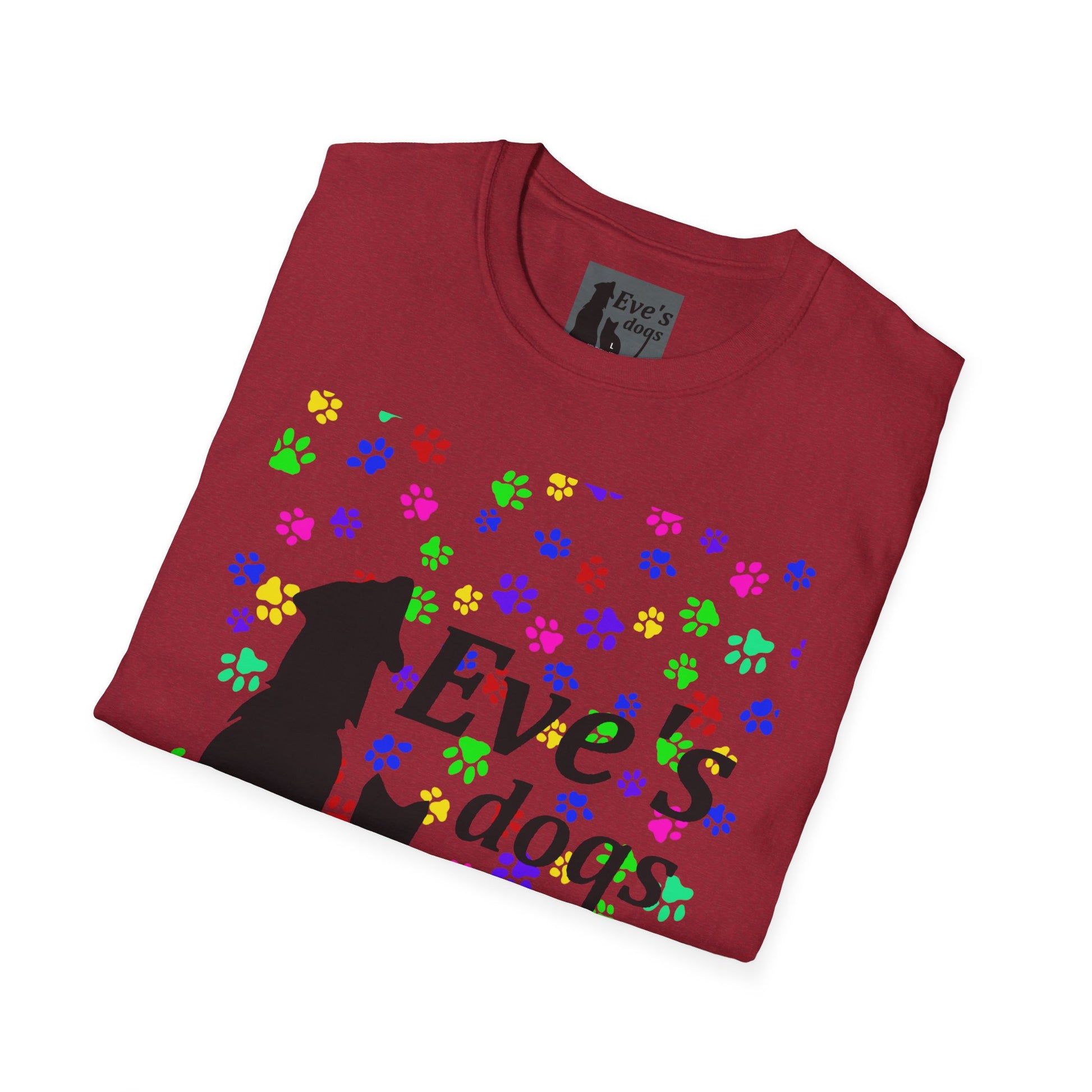 This is the Antique Cherry Red Adopt Eve's Dogs T-Shirt. It comes in XS - 5XL. The image is the shirt folded and showing the front. The size label is a grey and black tag with a dog and cat with the "Eve's dogs" writing. The front has pink, green, blue, purple, red paw prints in different sizes. Also, the dog and cat with "Eve's dogs" printed in black. It is against a white background.