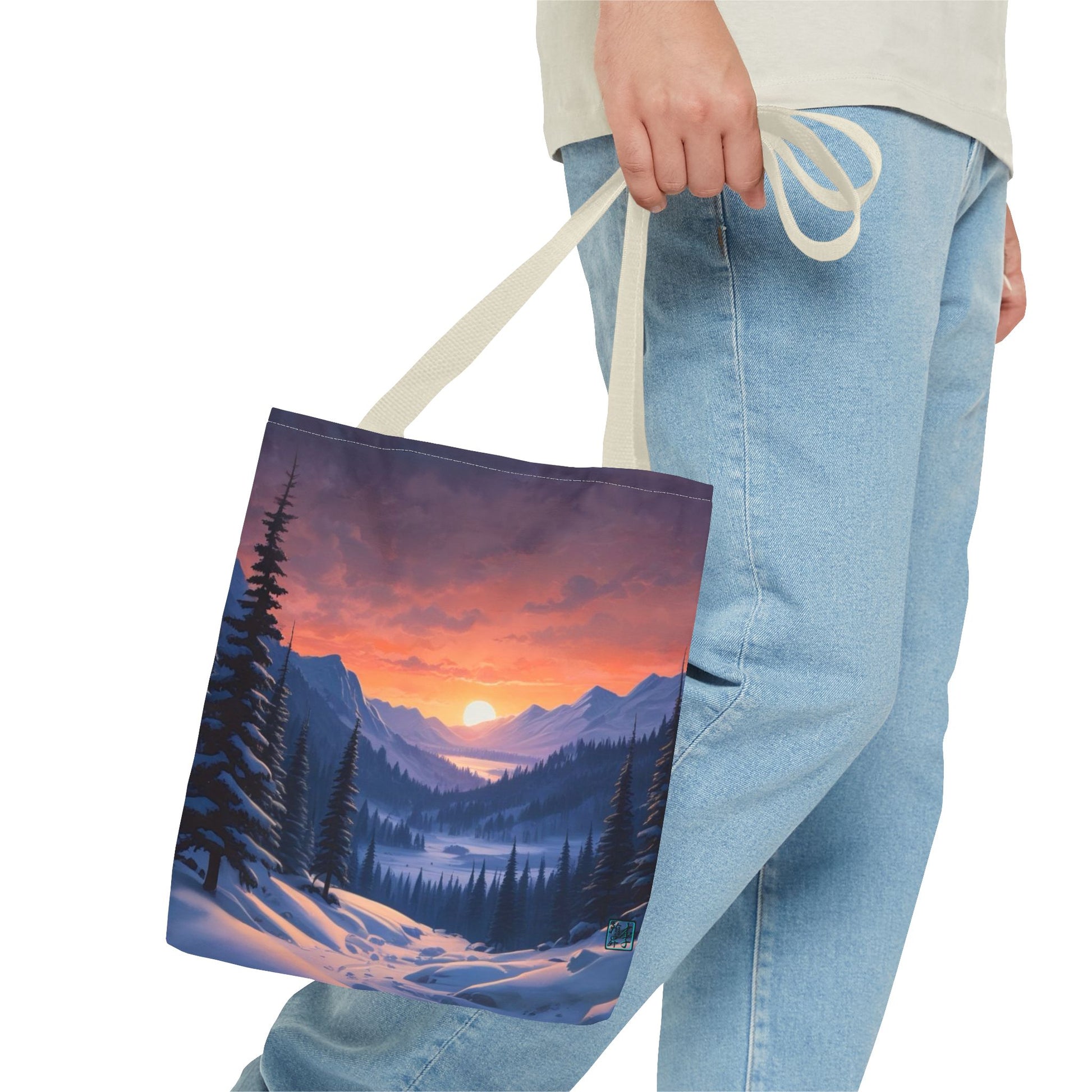 The Beige 13" x 13" Snow Valley Tote Bag has color matched handles and all around print. A man's hand with a beige tee and light- colored jeans is grabbing the handles from the hip down. The tote is against a white background.The design by Lee Hansheng Studios showcases a snowy hill/mountain area with large pine trees on both sides continuing into the horizon. The sun rises past the horizon consisting of yellow,orange,red hues illuminating onto wispy clouds,snowy field, mountains and dark green pine trees. 