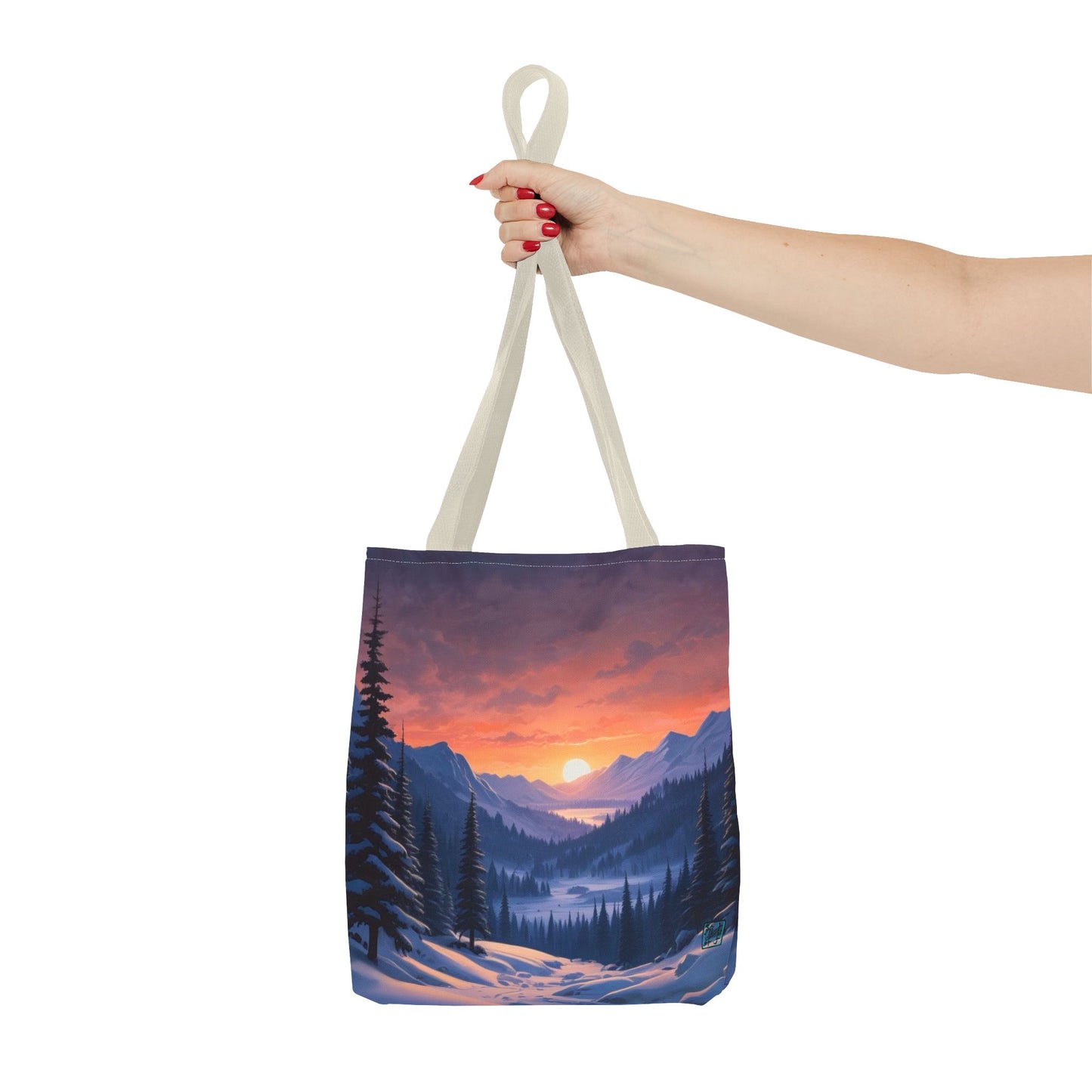 The Beige 16" x 16" Snow Valley Tote Bag has color matched handles and all around print.A woman's hand with red nail polish is grabbing the handles.Her arm is outstretched to the middle. The tote is against a white background.The design by Lee Hansheng Studios showcases a snowy hill/mountain area with large pine trees on both sides continuing into the horizon. The sun rises past the horizon consisting of yellow,orange,red hues illuminating onto wispy clouds,snowy field, mountains and dark green pine trees. 