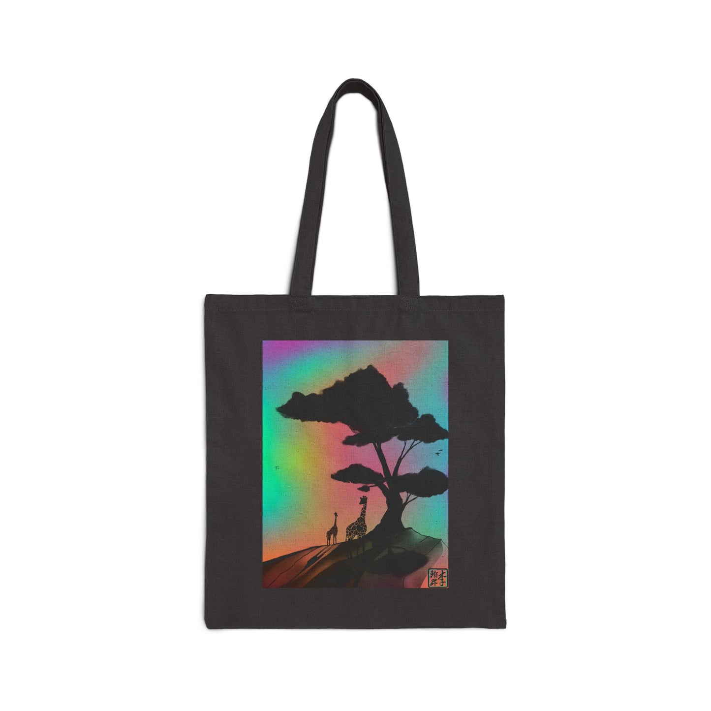 This is the Black 15" x 16" A Glance Tote Bag design by Lee Hansheng Studios. The handles are color matched. It is a sillhouette illustration in the middle of the shirt of a large tree rooted in the land. It is an orange red color with shadows reflected on it. One giraffe is in the foreground whereas the other is near the background spotted in black. The background is a mirage of pink, blue, yellow and red.