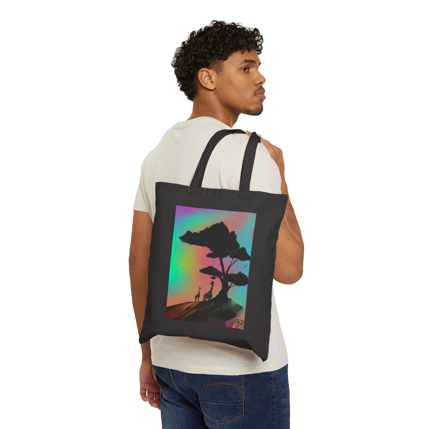 This is the Black 15" x 16" A Glance Tote Bag design by Lee Hansheng Studios. The handles are color matched.There is an African America ngentleman hanging the bag over his shoulder wearing a beige tee and jeans.It is a sillhouette illustration in the middle of the shirt of a large tree rooted in the land. It is an orange red color with shadows reflected on it. One giraffe is in the foreground whereas the other is near the background spotted in black. The background is a mirage of pink, blue, yellow and red.