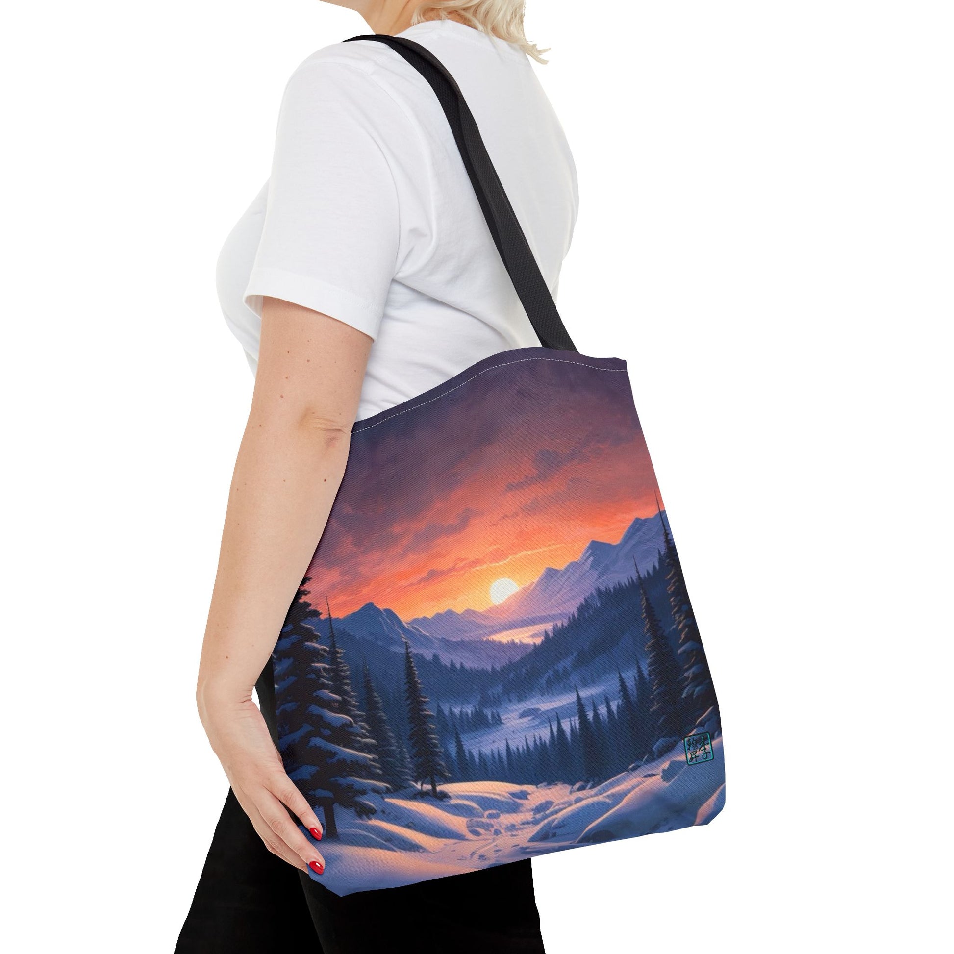 The Black 16" x 16" Snow Valley Tote Bag has color matched handles. A lady with short blonde hair,white tee plus black pants with tote around their shoulder and hand in pocket against a white background.The design by Lee Hansheng Studios showcases a snowy hill/mountain area with large pine trees on both sides continuing into the horizon. The sun rises past the horizon consisting of yellow,orange,red hues illuminating onto wispy clouds,snowy field, mountains and dark green pine trees. 