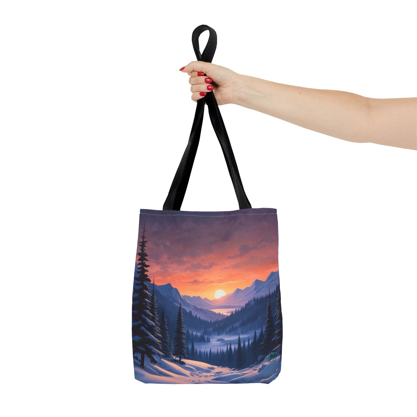 The Black 16" x 16" Snow Valley Tote Bag has color matched handles and all around print.A woman's hand with red nail polish is grabbing the handles.Her arm is outstretched to the middle. The tote is against a white background.The design by Lee Hansheng Studios showcases a snowy hill/mountain area with large pine trees on both sides continuing into the horizon. The sun rises past the horizon consisting of yellow,orange,red hues illuminating onto wispy clouds,snowy field, mountains and dark green pine trees. 