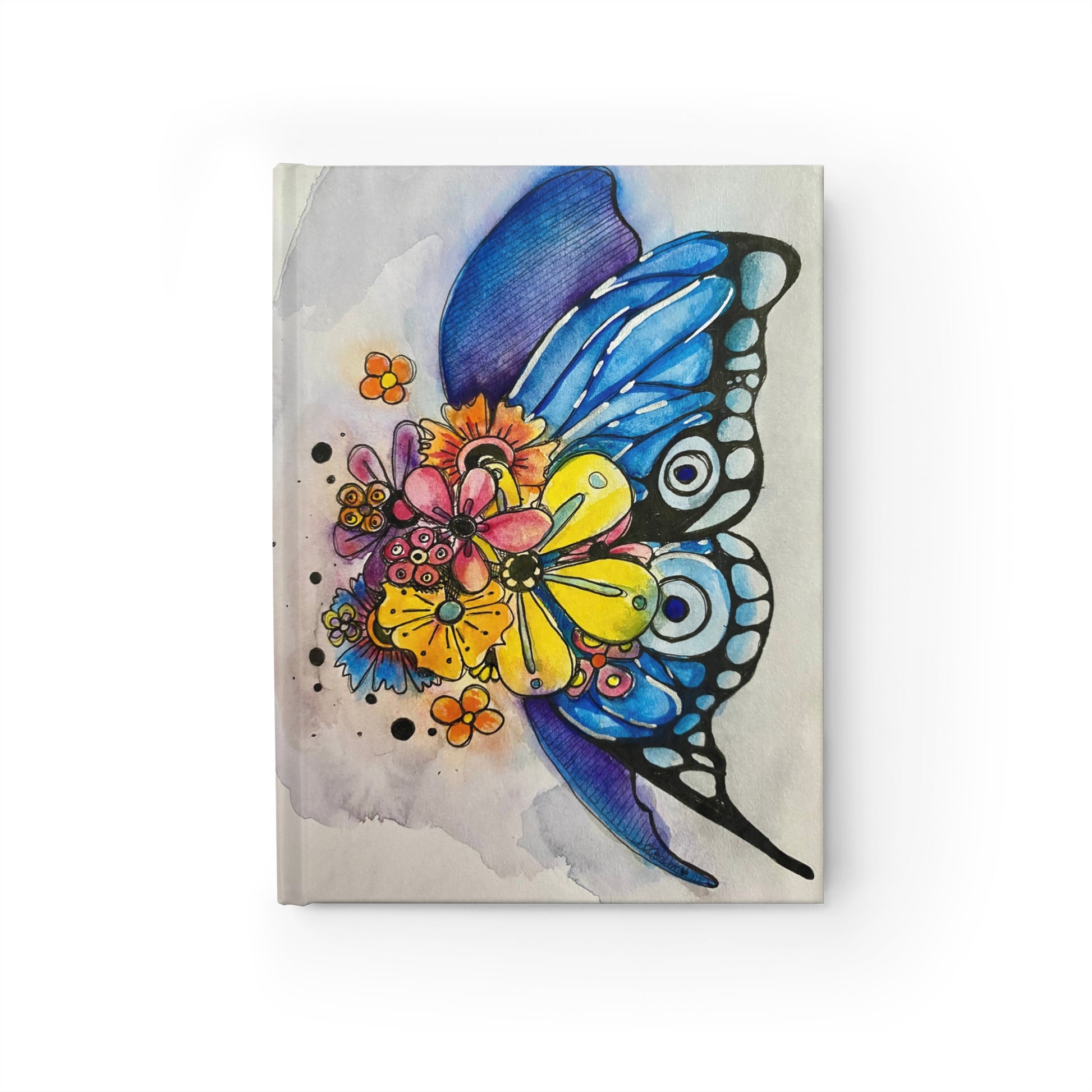 This is the Blooming Sketchbook Journal by Storm Garden Studio. This shows the front. It is an illustration of a water colored blue butterfly with bursting flowers covering it's body. There are various flowers with colors of orange, yellow, red, purple and blue. The back wing is mixed between blue and purple.  The background is a mized between purple and red spread around lightly. The base color of the journal is more tan/beige. The journal is against a white background.