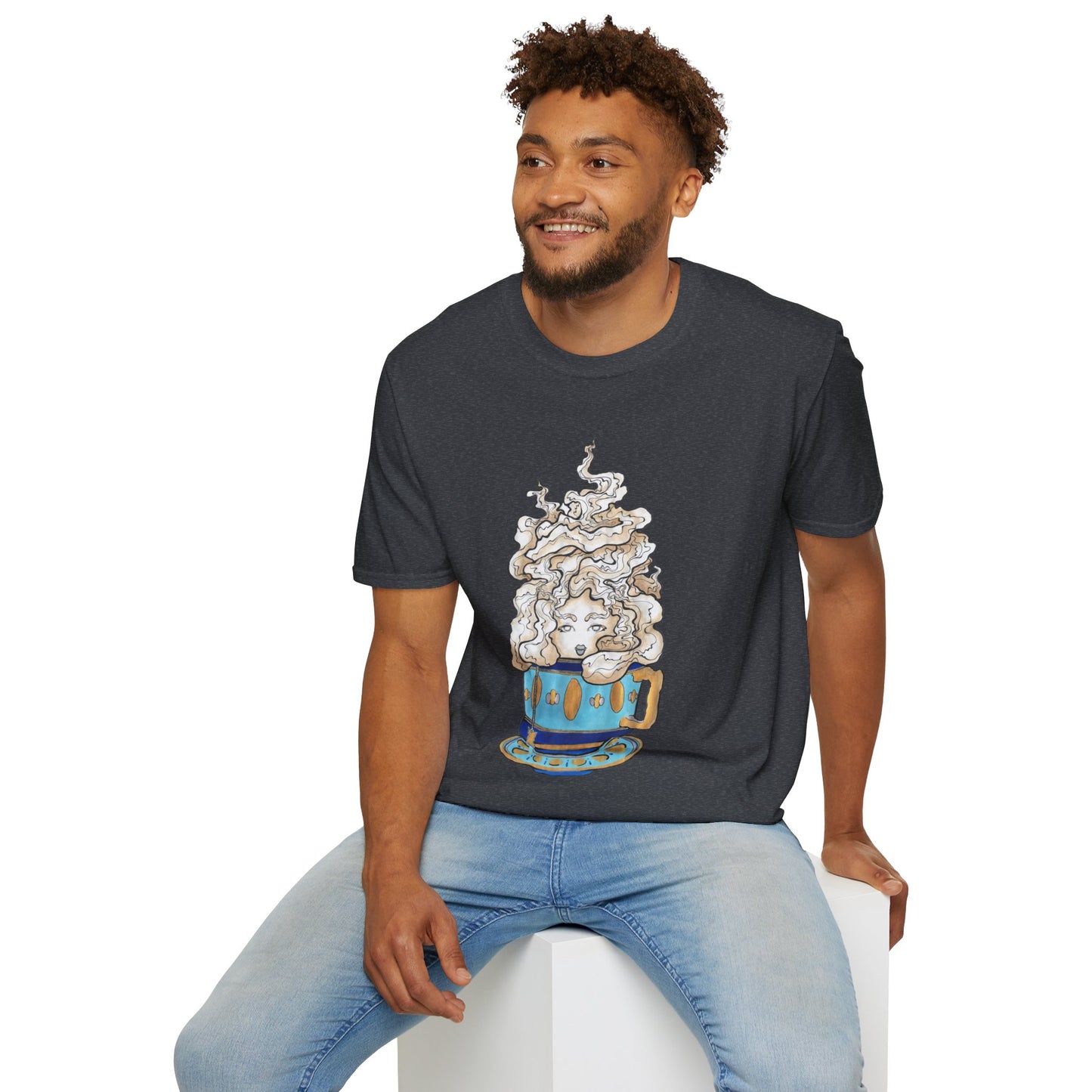 This is the Dark Heather Grey Earl Grey Softstyle T-Shirt by Chris Foster Design. It comes in sizes XS-5XL. The illustration is of a gold, light blue and dark blue teacup with a tan, yellow and white steam. The steam is swirly and goes up and outwards. In the middle is a lady's face. A smiling man sitting on a white podium with one hand on the back edge, light jeans, looking to the left and wearing the t-shirt. 