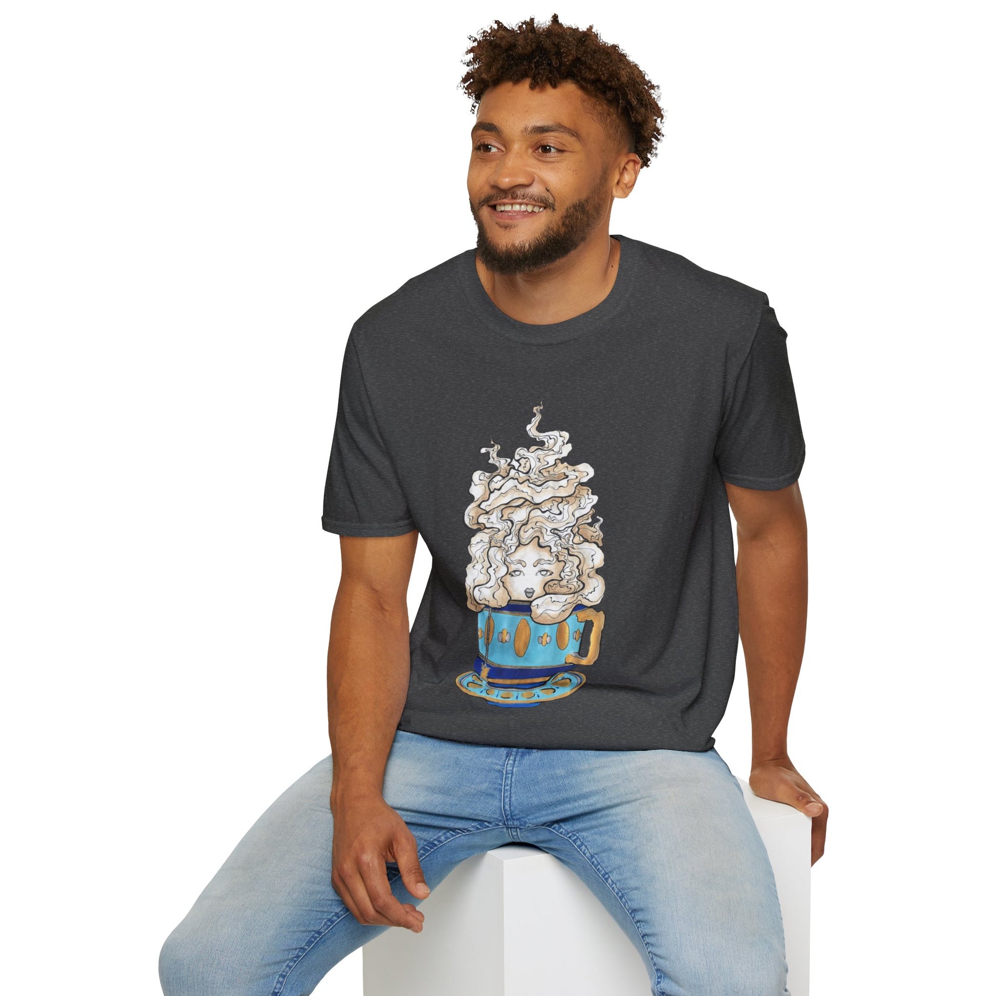 This is the Dark Heather Earl Grey Softstyle T-Shirt by Chris Foster Design. It comes in sizes XS-5XL. The illustration is of a gold, light blue and dark blue teacup with a tan, yellow and white steam. The steam is swirly and goes up and outwards. In the middle is a lady's face. A smiling man sitting on a white podium with one hand on the back edge, light jeans, looking to the left and wearing the t-shirt. 