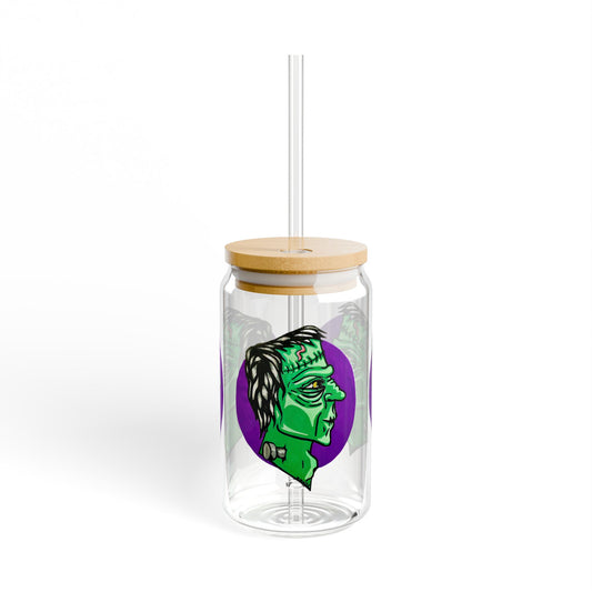 This is the 16oz Frankensteins Monster Sipper Glass with light colored bamboo lid and with straw to the front by Storm Garden Studio. It is a side profile illustration of Frankenstein printed all around. He is facing the right side, a scar across the forehead, orange/yellow scar on the top of the forehead and a silver screw. He is all over green with shading on chin, cheeks and highbones. It is against a white background.