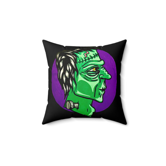 This is the 14" x 14" Frankensteins Monster Spun Polyester Square Pillow by Storm Garden Studio. The pillow overall is black and the illustration are on both sides. This showcases the front of the pillow. It is Frankenstein's side profile illustration. He is facing the right side, a scar across the forehead, orange/yellow scar on the top of the forehead and a silver screw. He is all over green with shading on chin, cheeks and highbones. It is against a white background.