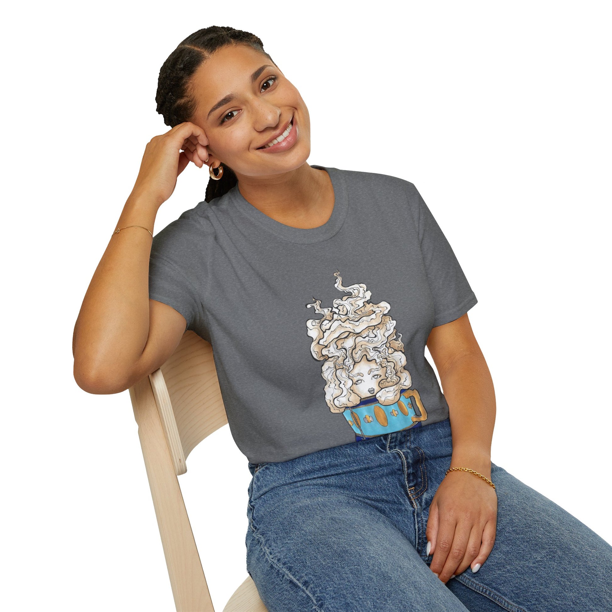 This is the Graphite Heather Earl Grey Softstyle T-Shirt by Chris Foster Design. It comes in sizes XS-5XL. The illustration is of a gold, light blue and dark blue teacup with a tan, yellow and white steam. The steam is swirly and goes up and outwards. In the middle is a lady's face. A smiling lady is sitting on a light wood chair with the backrest to the left, elbow on the back rest, dark jeans, looking to the front and wearing the t-shirt. 