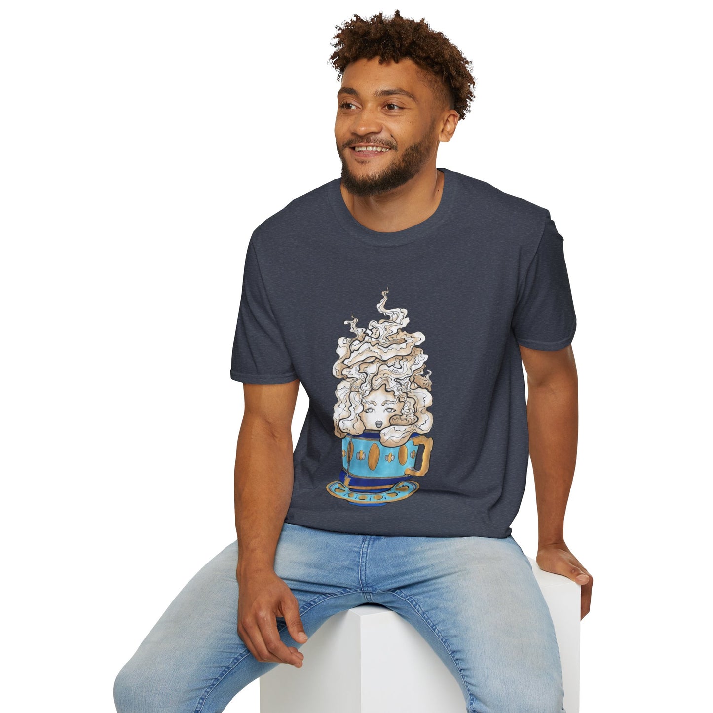 This is the Heather Navy Grey Earl Grey Softstyle T-Shirt by Chris Foster Design. It comes in sizes XS-5XL. The illustration is of a gold, light blue and dark blue teacup with a tan, yellow and white steam. The steam is swirly and goes up and outwards. In the middle is a lady's face. A smiling man sitting on a white podium with one hand on the back edge, light jeans, looking to the left and wearing the t-shirt. 