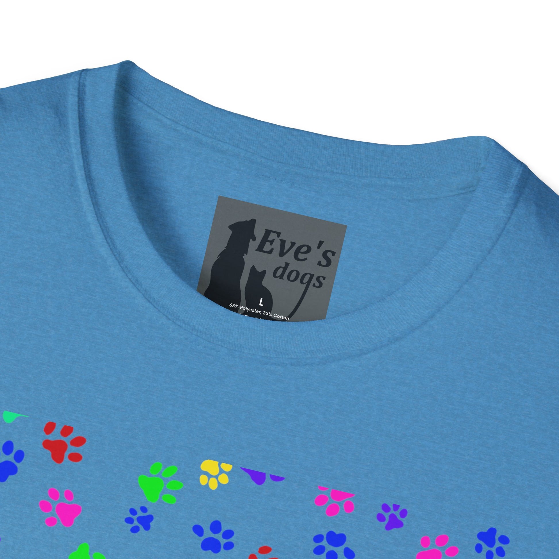 This is the Heather Sapphire Adopt Eve's Dogs T-Shirt. It comes in XS - 5XL. This is an upclose image of the shirt where the neck/tag is. The size label is a grey and black tag with a dog and cat with the "Eve's dogs" writing. The sizes and shirt product materials are printed in white. There is a little bit of paw prints on the front.  The colors are pink, green, blue, purple, red paw prints in different sizes. It is against a white background.