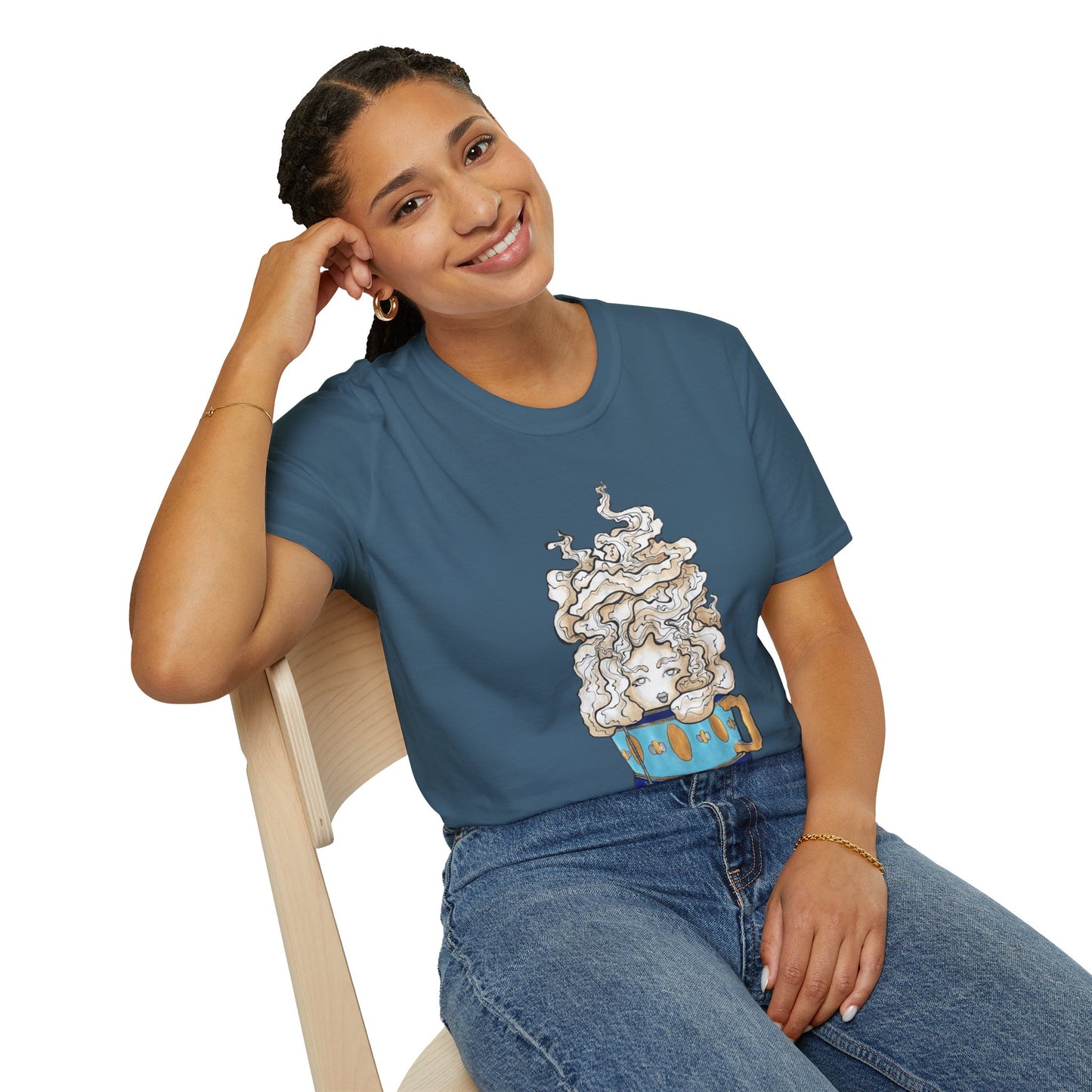 This is the Indigo Blue Earl Grey Softstyle T-Shirt by Chris Foster Design. It comes in sizes XS-5XL. The illustration is of a gold, light blue and dark blue teacup with a tan, yellow and white steam. The steam is swirly and goes up and outwards. In the middle is a lady's face. A smiling lady is sitting on a light wood chair with the backrest to the left, elbow on the back rest, dark jeans, looking to the front and wearing the t-shirt. 