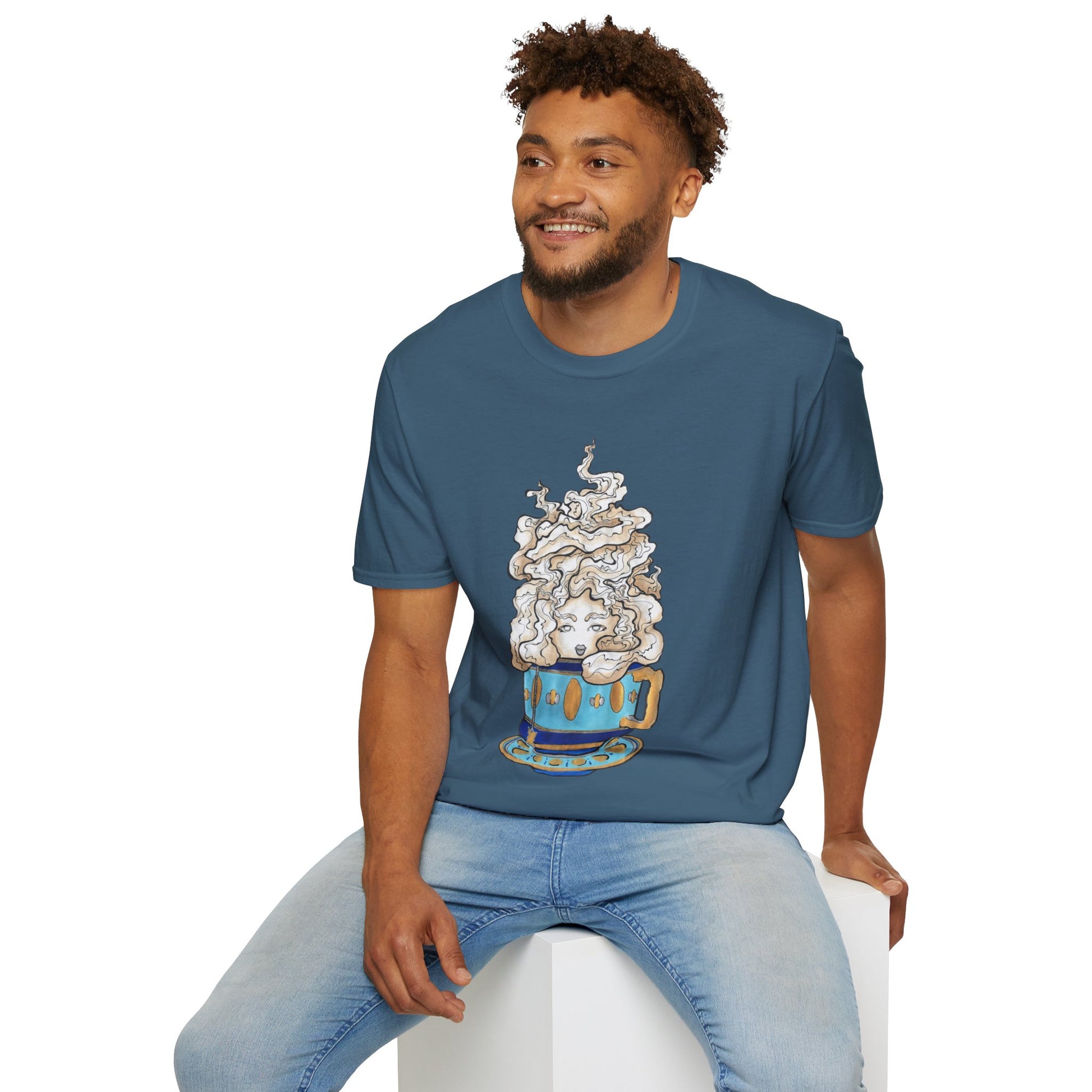 This is the Indigo Blue Earl Grey Softstyle T-Shirt by Chris Foster Design. It comes in sizes XS-5XL. The illustration is of a gold, light blue and dark blue teacup with a tan, yellow and white steam. The steam is swirly and goes up and outwards. In the middle is a lady's face. A smiling man sitting on a white podium with one hand on the back edge, light jeans, looking to the left and wearing the t-shirt. 