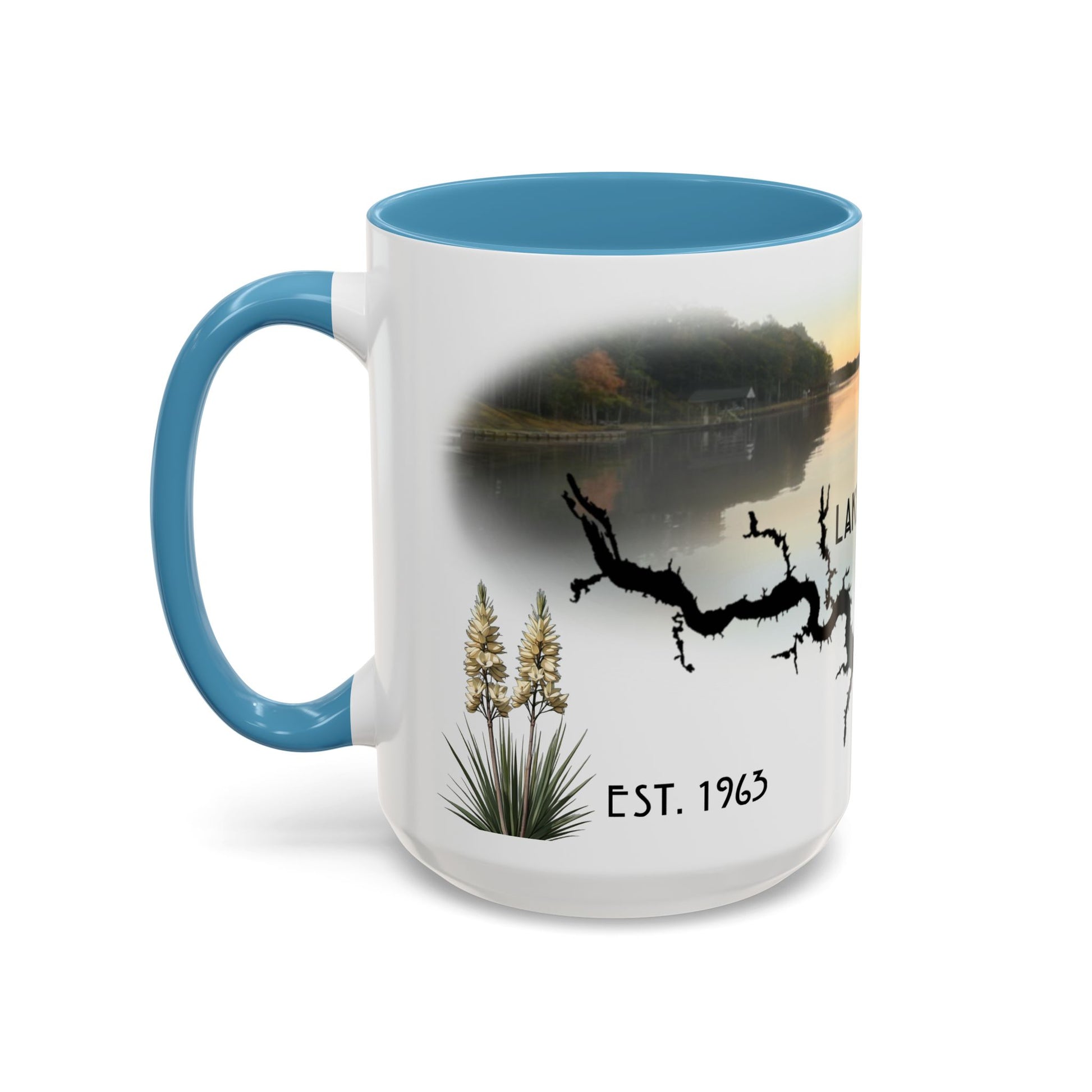 This is the 15oz Light Blue Lake Gaston Mug. It is an illustration by Lee Hansheng Studios. The picture is shown from the left side of the mug. The handle and inside of mug are color matched too. The mug is all white except for the illustration and handle. The illustration shows some yucca plants on the left, serene depiction of the lake in the back, the shadow of a tree and "EST.1963". The mug is against a white background in the picture too.