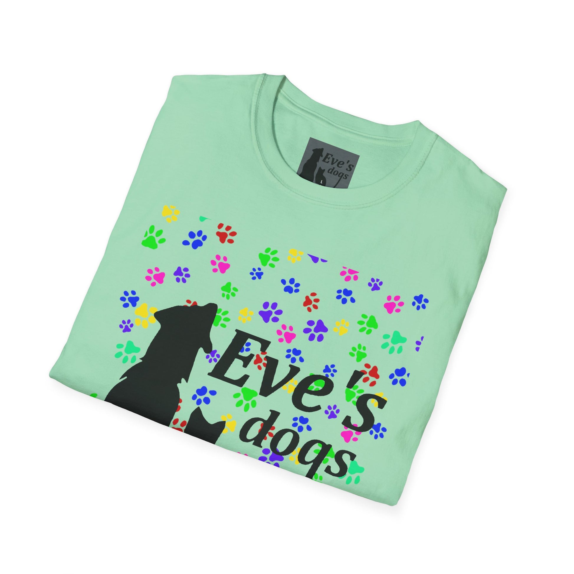 This is the Mint Green Adopt Eve's Dogs T-Shirt. It comes in XS - 5XL. The image is the shirt folded and showing the front. The size label is a grey and black tag with a dog and cat with the "Eve's dogs" writing. The front has pink, green, blue, purple, red paw prints in different sizes. Also, the dog and cat with "Eve's dogs" printed in black. It is against a white background.