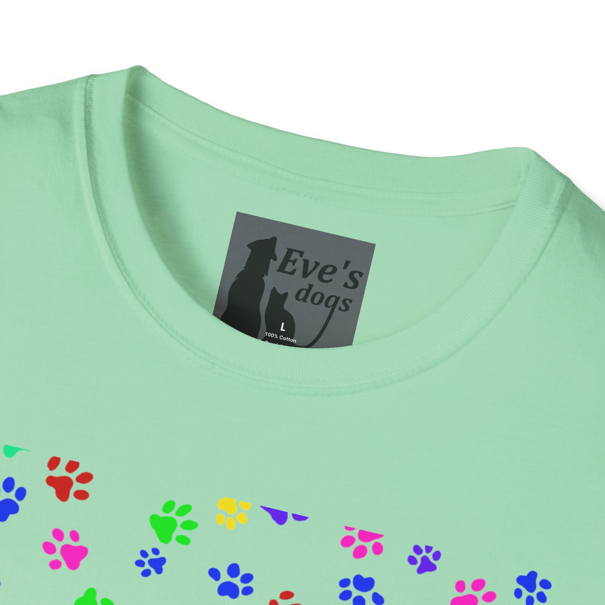 This is the Mint Green Adopt Eve's Dogs T-Shirt. It comes in XS - 5XL. This is an upclose image of the shirt where the neck/tag is. The size label is a grey and black tag with a dog and cat with the "Eve's dogs" writing. The sizes and shirt product materials are printed in white. There is a little bit of paw prints on the front.  The colors are pink, green, blue, purple, red paw prints in different sizes. It is against a white background.